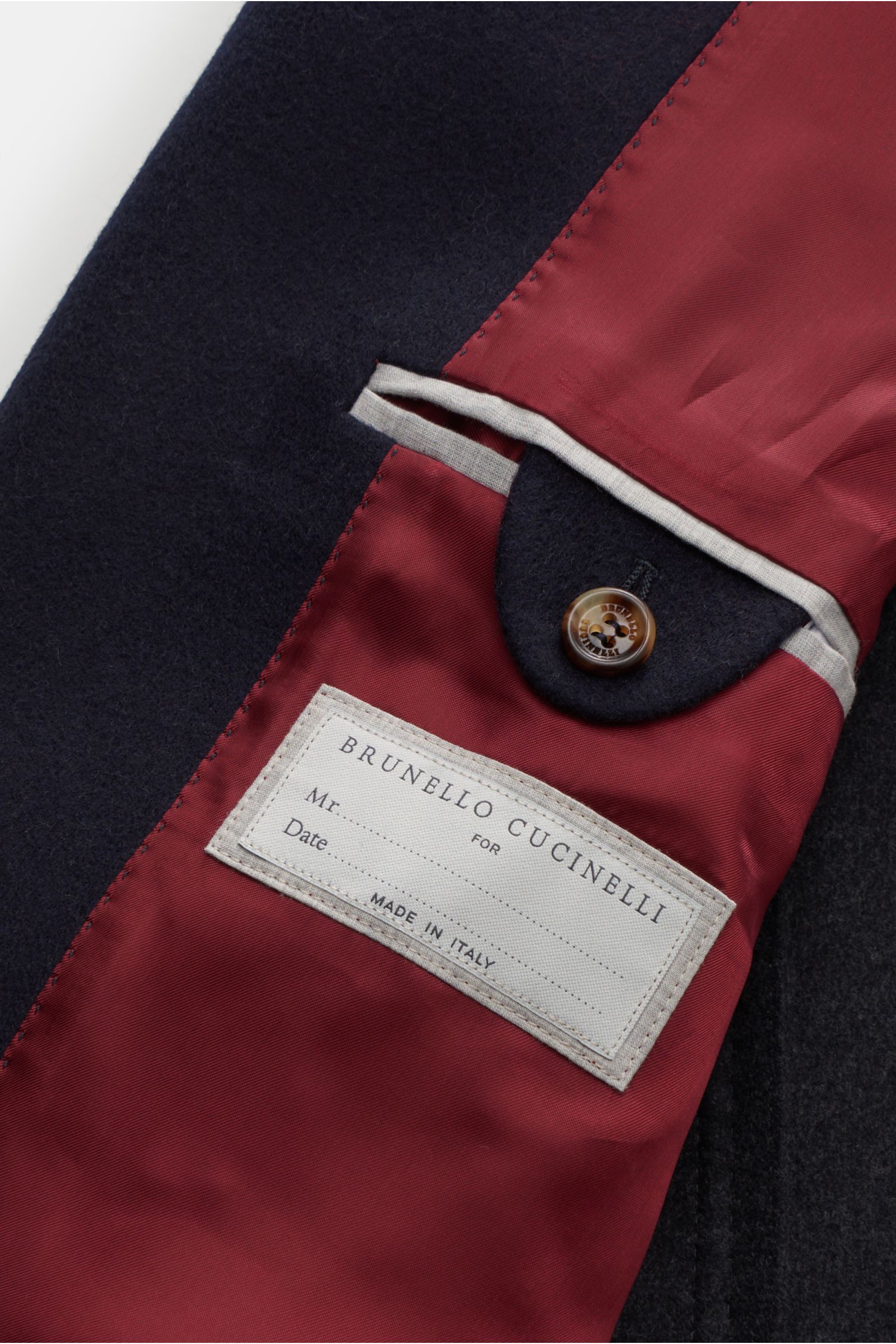 Close-up inside view of the Brunello Cucinelli Coat navy showing soft wool fabric and elegant red lining with label and button detail.

Look forward to the cold weather: The luxurious unconstructed coat by Italian label BRUNELLO CUCINELLI, made of soft