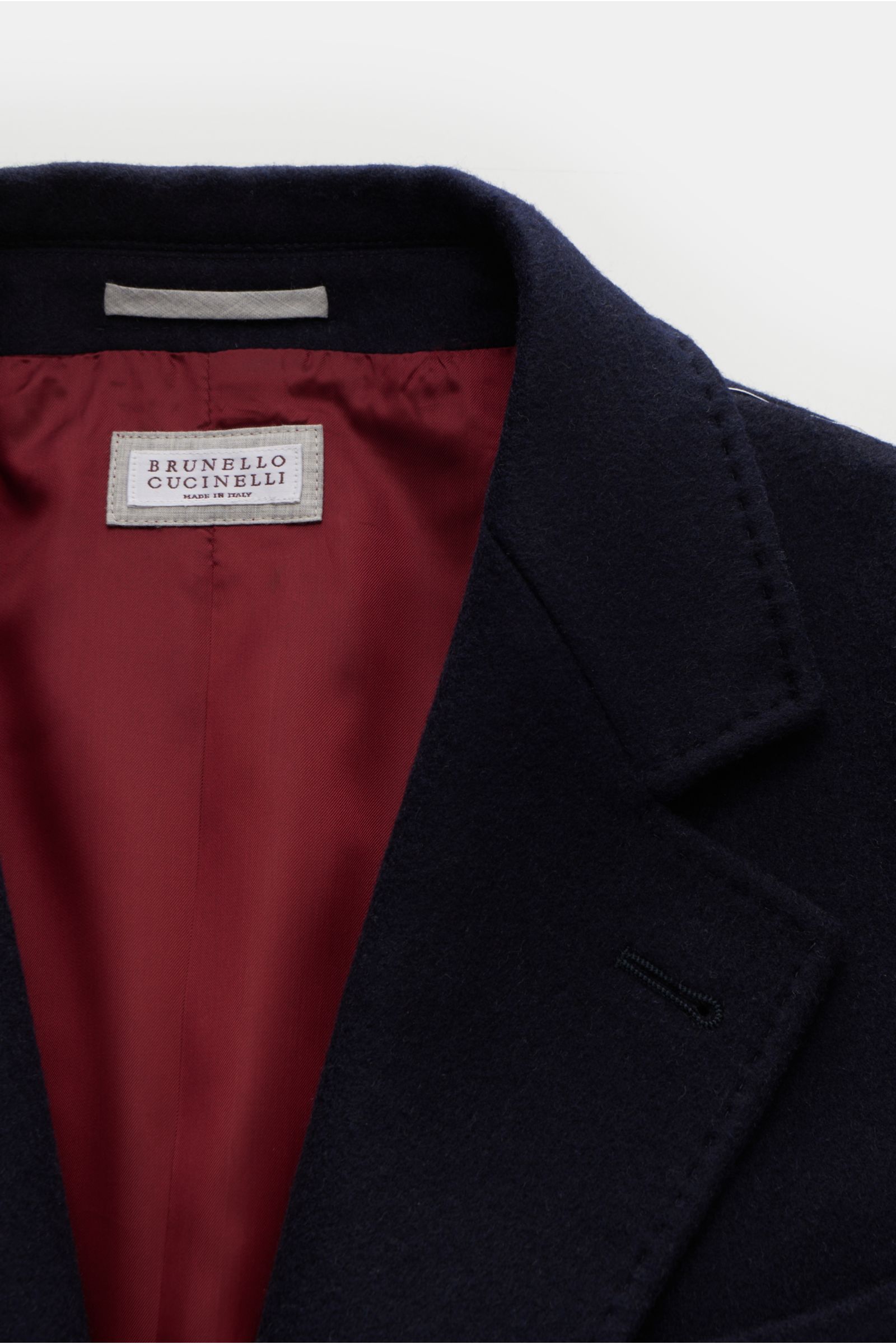 Close-up front view of the Brunello Cucinelli Coat navy, showing the soft wool fabric and elegant red lining. Look forward to the cold weather: The luxurious unconstructed coat by Italian label BRUNELLO CUCINELLI, made of soft wool and enhanced with an el