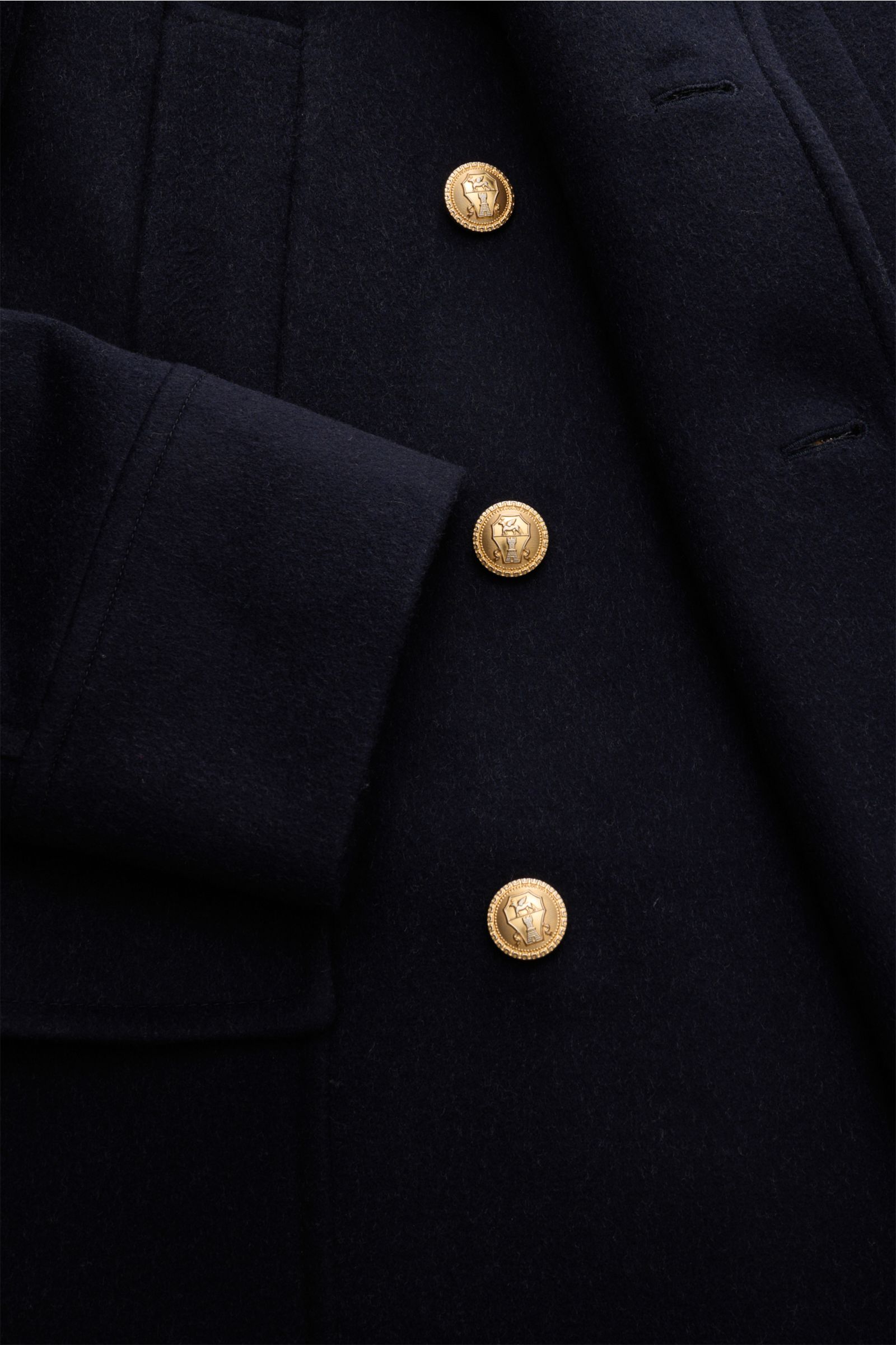 Nahaufnahme aus schräger Perspektive des luxuriösen Brunello Cucinelli Wollmantels navy aus reiner, weicher Wolle mit doppeltreiher Drei-Knopf-Stil.