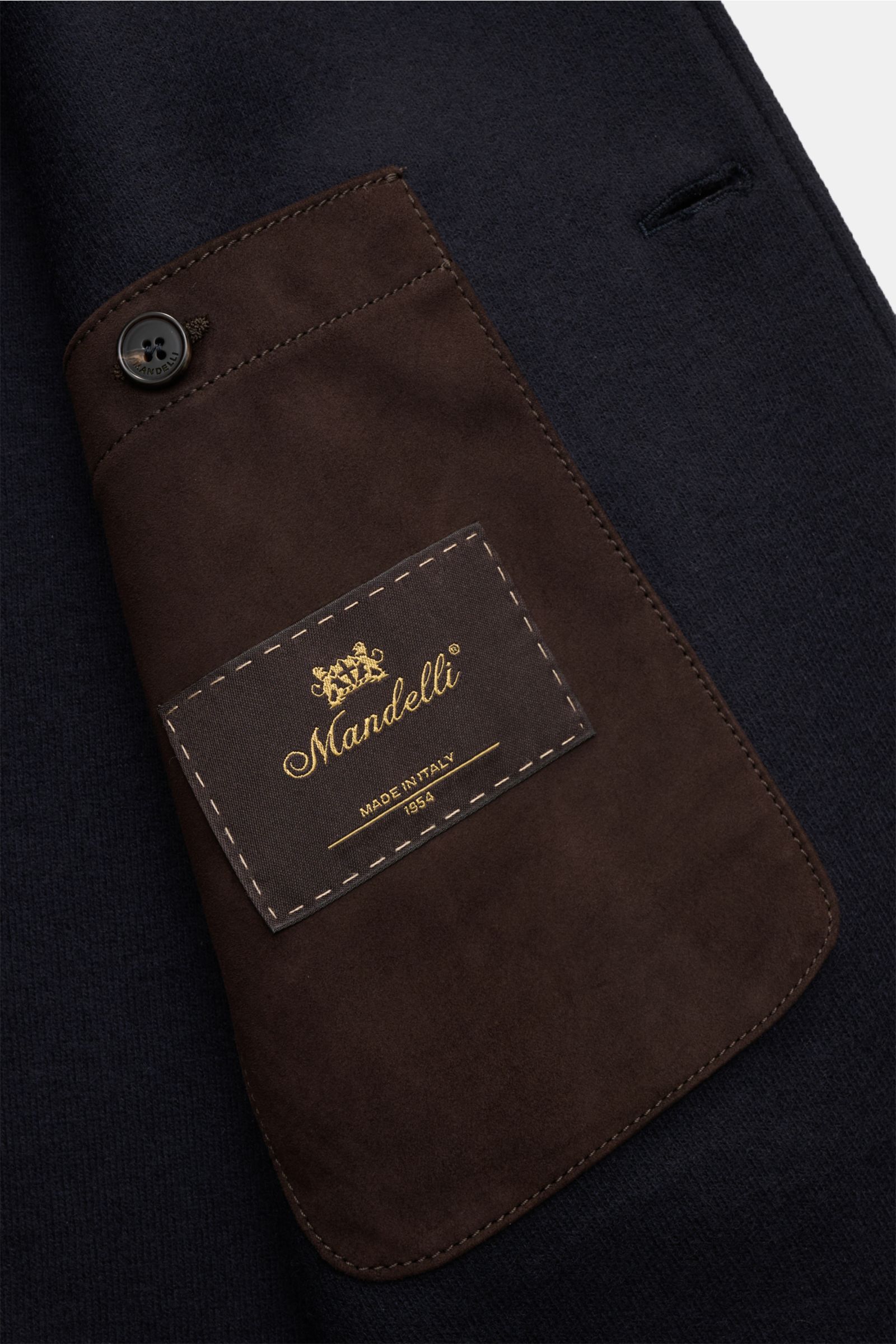 Nahaufnahme des Mandelli Jersey-Mantel navy mit Ziegenveloursleder-Besatz und Markenlabel, Detailansicht des Innenfutters.