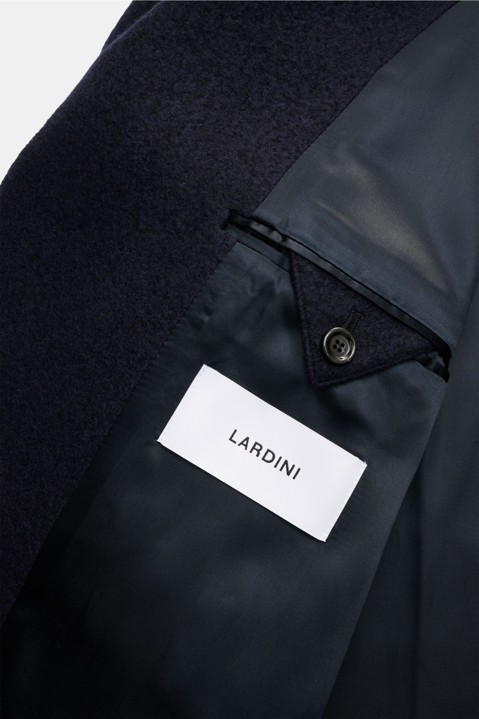 Close-up inside view of the Lardini Mantel navy showing soft navy fabric, button detail, and white Lardini label on tonal lining.

Ein perfekter Mantel vereint zeitloses Design, eine klassische Silhouette und erlesene Materialien wie Cashmere, Seide un