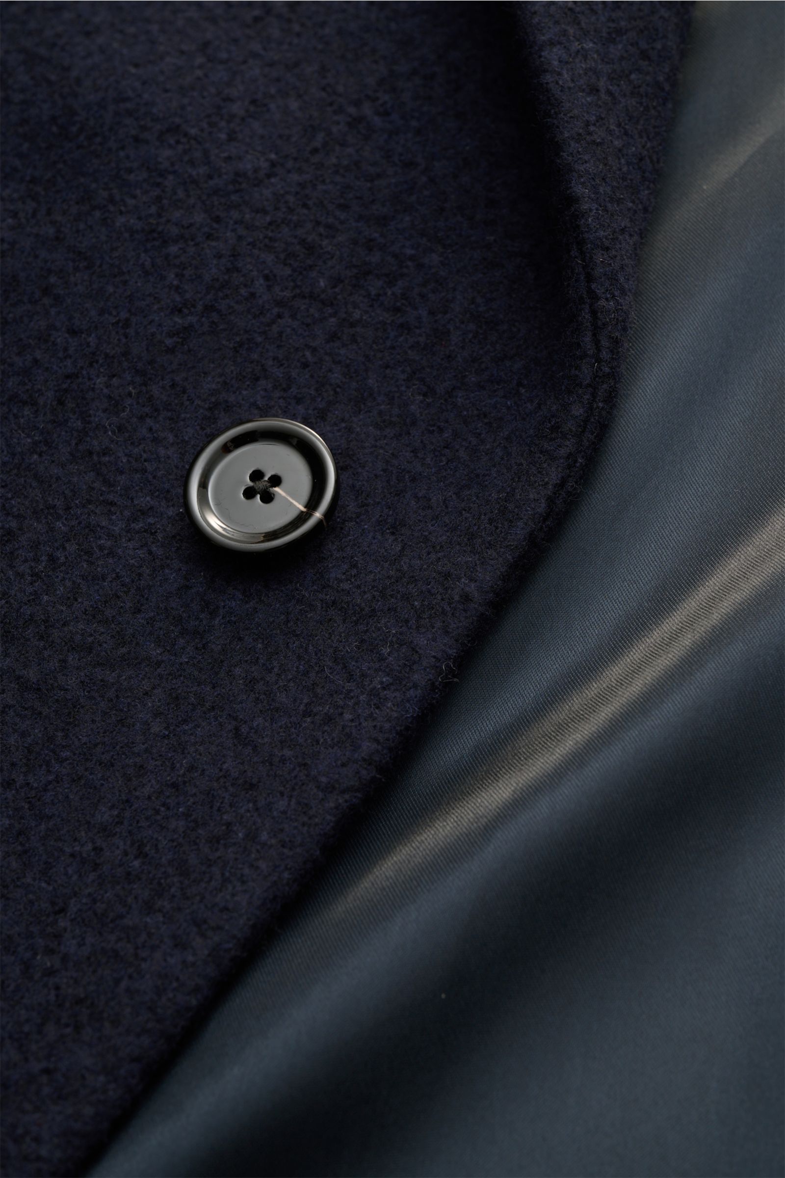 Close-up of Lardini Mantel navy showing a black button on textured navy fabric next to smooth navy lining, photographed from above.

Description: Ein perfekter Mantel vereint zeitloses Design, eine klassische Silhouette und erlesene Materialien wie Cas