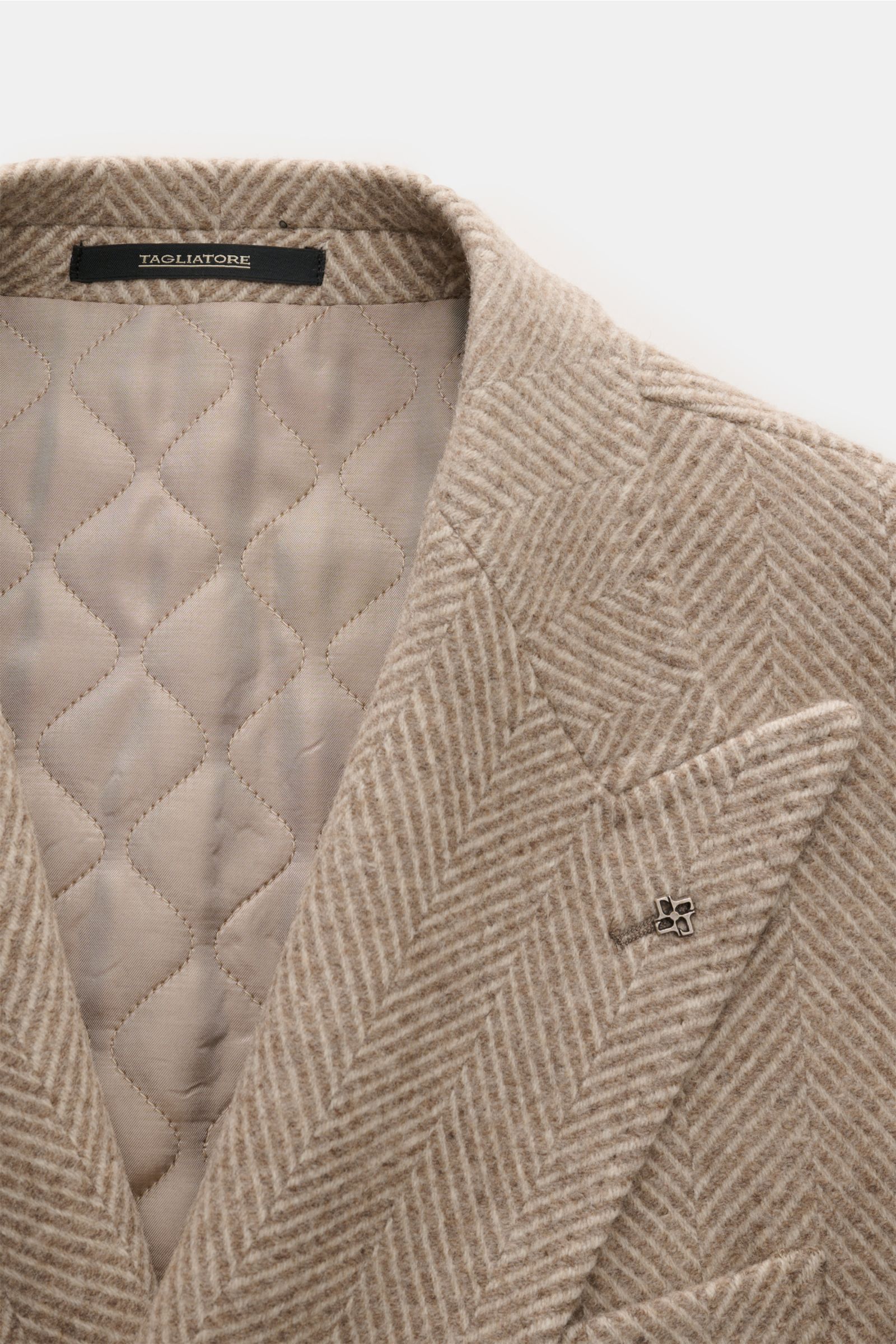 Nahaufnahme von Tagliatore Wollmantel beige/creme gemustert mit elegantem Fischgratmuster, Slim Fit, zweireihigem Drei-Knopf-Stil, Spitzrevers mit Logo-Pin und paspelierter Brusttasche, halb gefüttert, aus Schurwoll-Cashmere-Mix, weicher Griff.