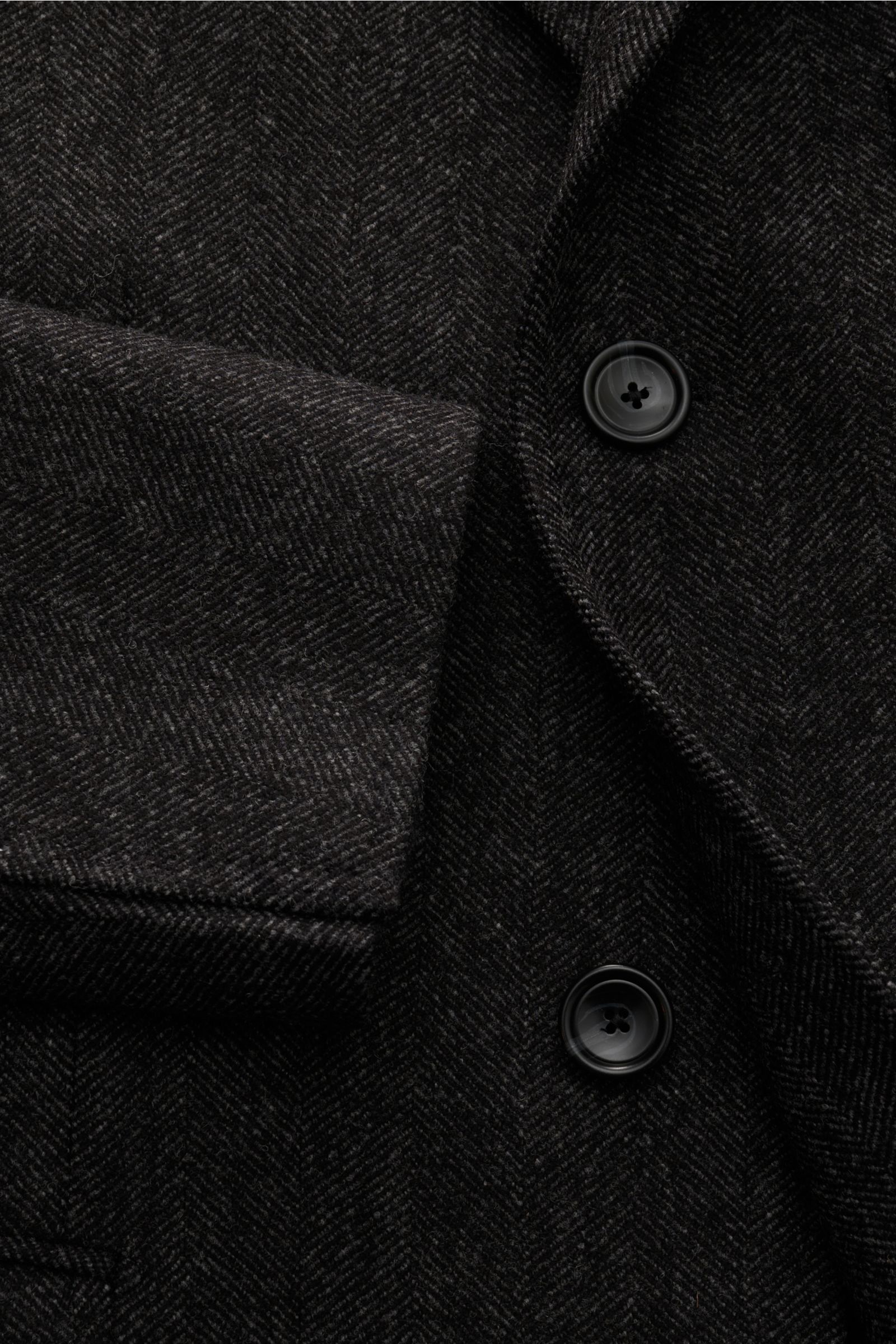 Nahaufnahme des Tagliatore Mantel schwarz/grau gemustert aus Schurwolle und Cashmere mit Fischgrat-Muster, Slim Fit, Drei-Knopf-Leiste und weichem Griff.