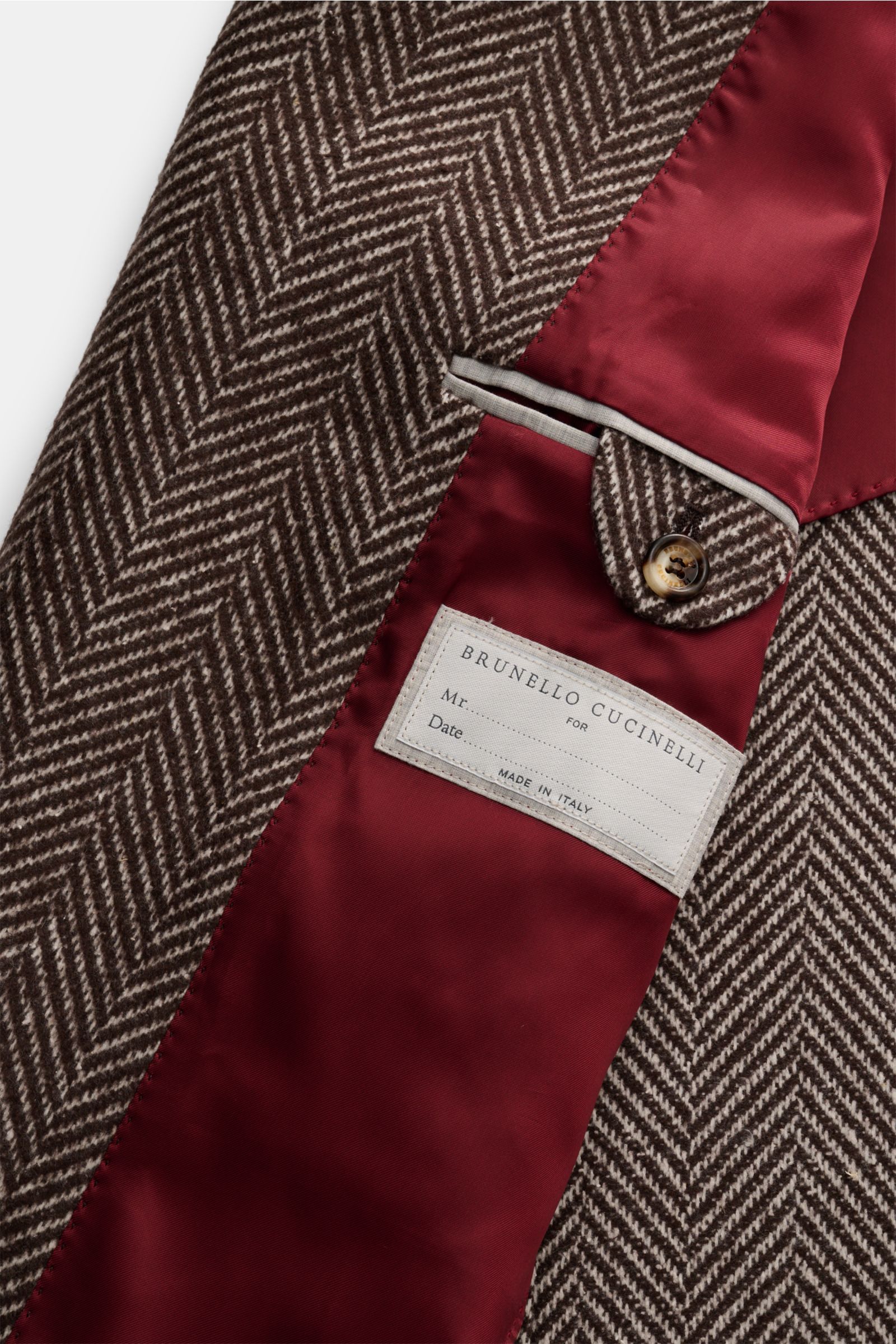 Brunello Cucinelli Mantel dunkelbraun/offwhite gestreift, Detailaufnahme innen mit Fischgrat-Webmuster, rotem Futter, Knopf und Label, Mix aus Cashmere und Seide.