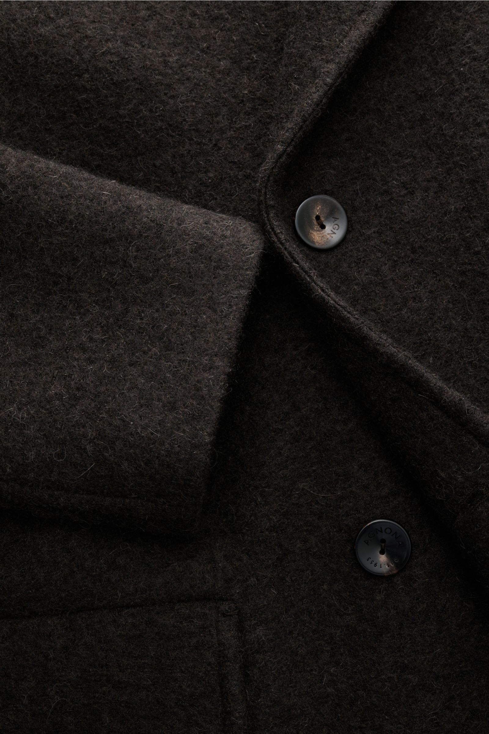 A close-up front view of the Agnona Cashmere Mantel anthrazit showing its soft twill cashmere fabric, five-button placket, and angled pocket with detailed buttons. Der cleane Cashmere-Mantel von AGNONA überzeugt mit puristischer Eleganz und einer leich