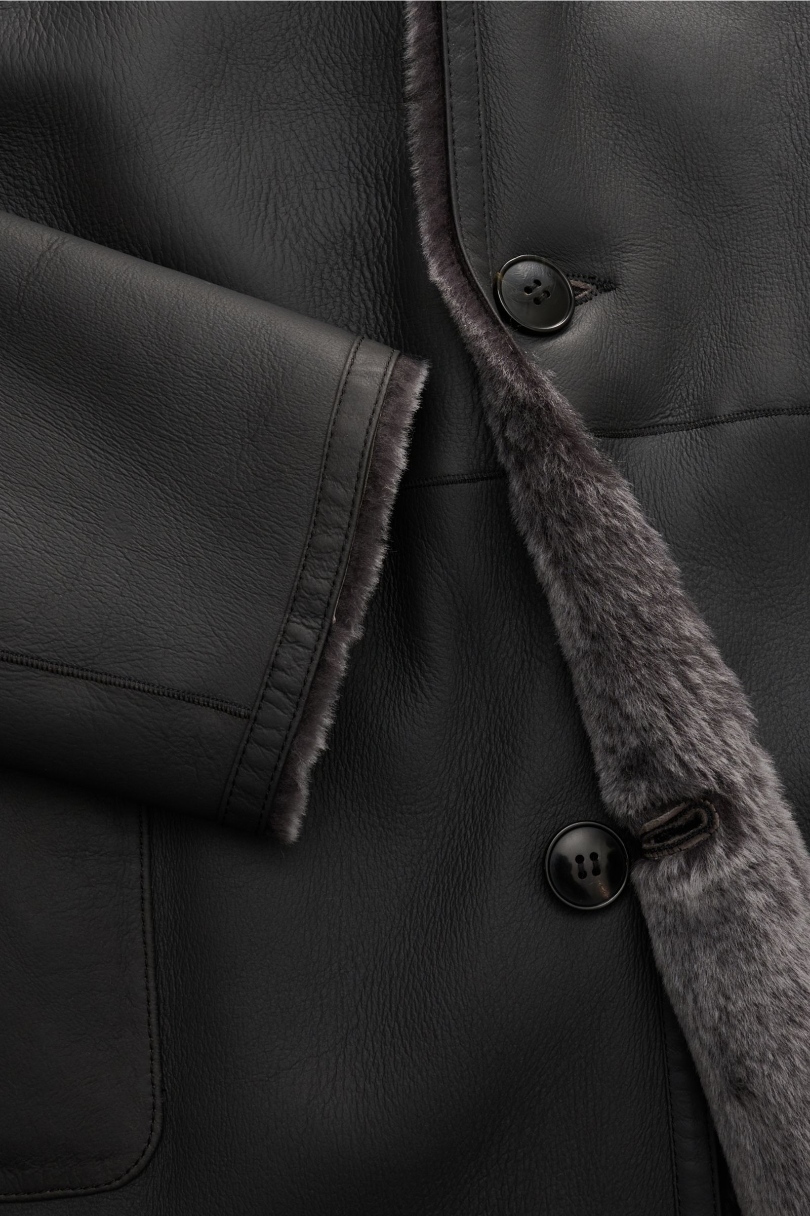 Manzoni 24 Lammfellmantel anthrazit in Nahaufnahme von vorne, weiches Lammleder, Reverskragen mit Lammfell, Slim Fit, drei Knöpfe, aufgesetzte Taschen.