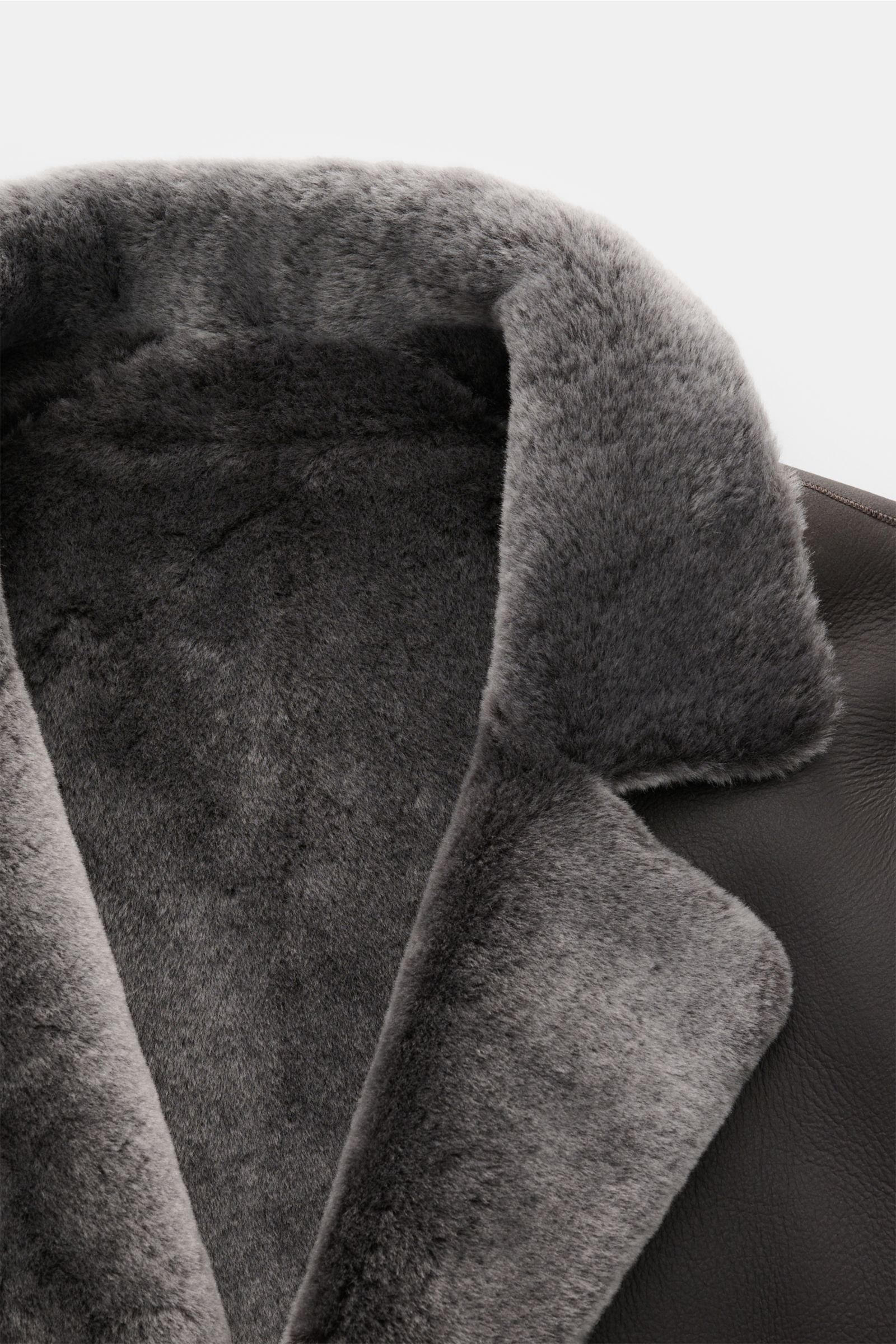 Nahaufnahme des Reverskragens des Manzoni 24 Lammfellmantels graubraun aus weichem Lammfell mit Slim Fit und drei Knöpfen.