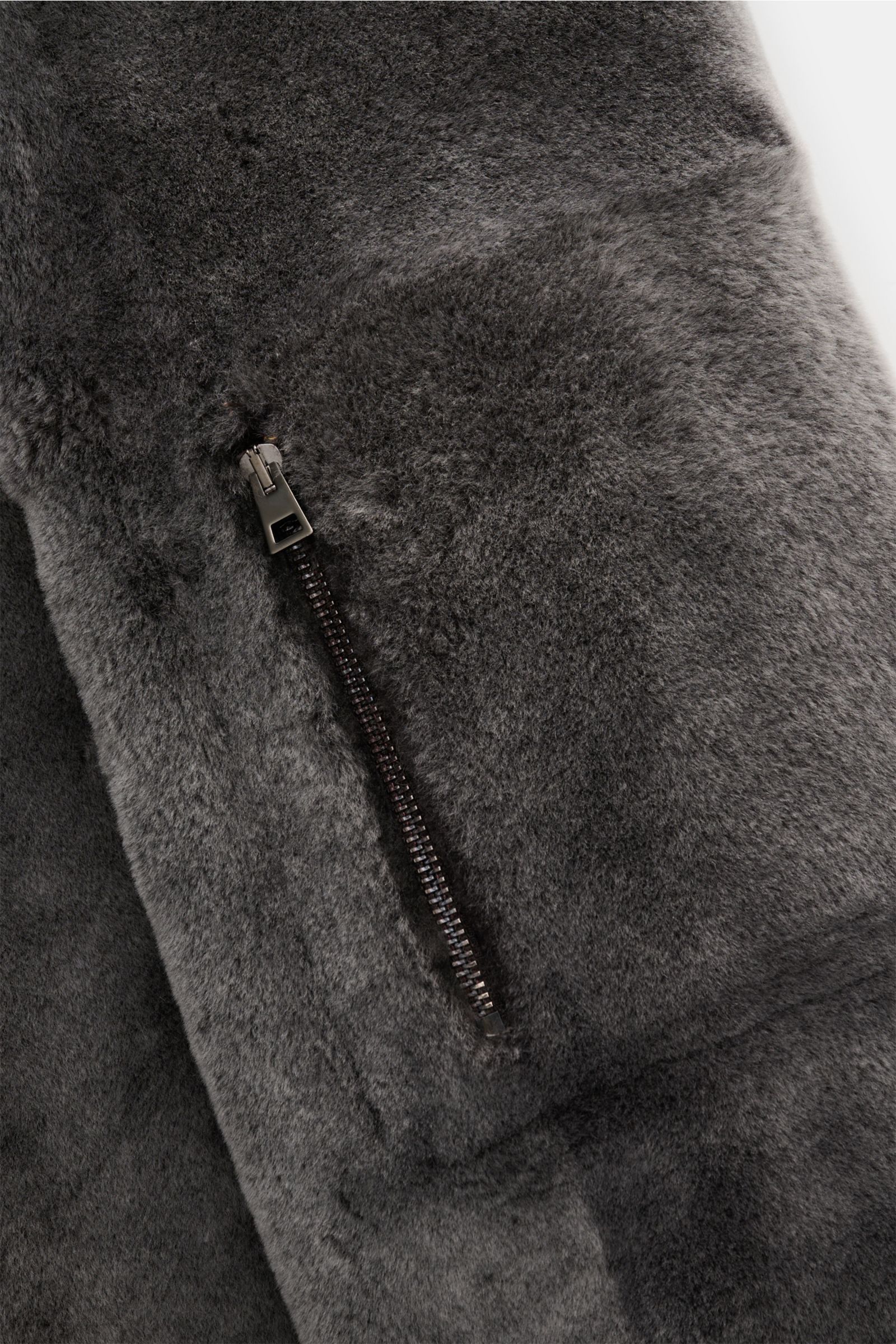 Nahaufnahme des graubraunen Manzoni 24 Lammfellmantels mit weichem Griff, Reißverschlussdetail, weichem Lammfell und Slim Fit Schnitt.