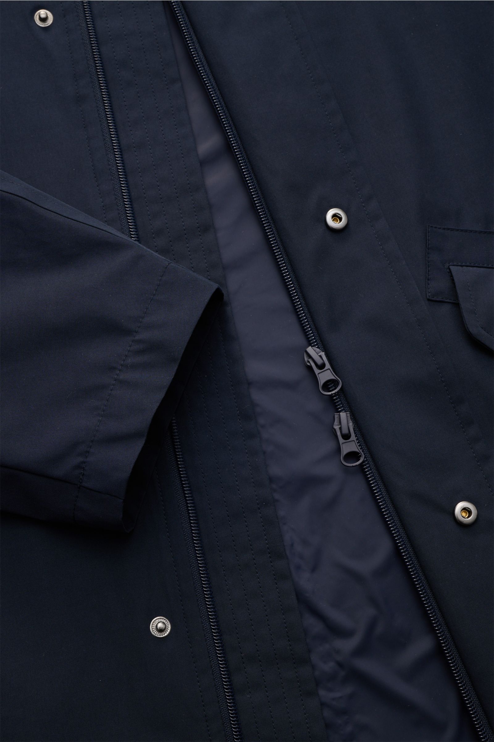 Close-up front view of the A.P.C. Parka 'Antonin' navy showing the smooth microfiber and cotton fabric, two-way zipper, snap buttons, and part of a flap pocket. Der Parka 'Antonin' in leichter Qualität mit dichtem Gewebe aus hochwertiger Microfaser und Ba