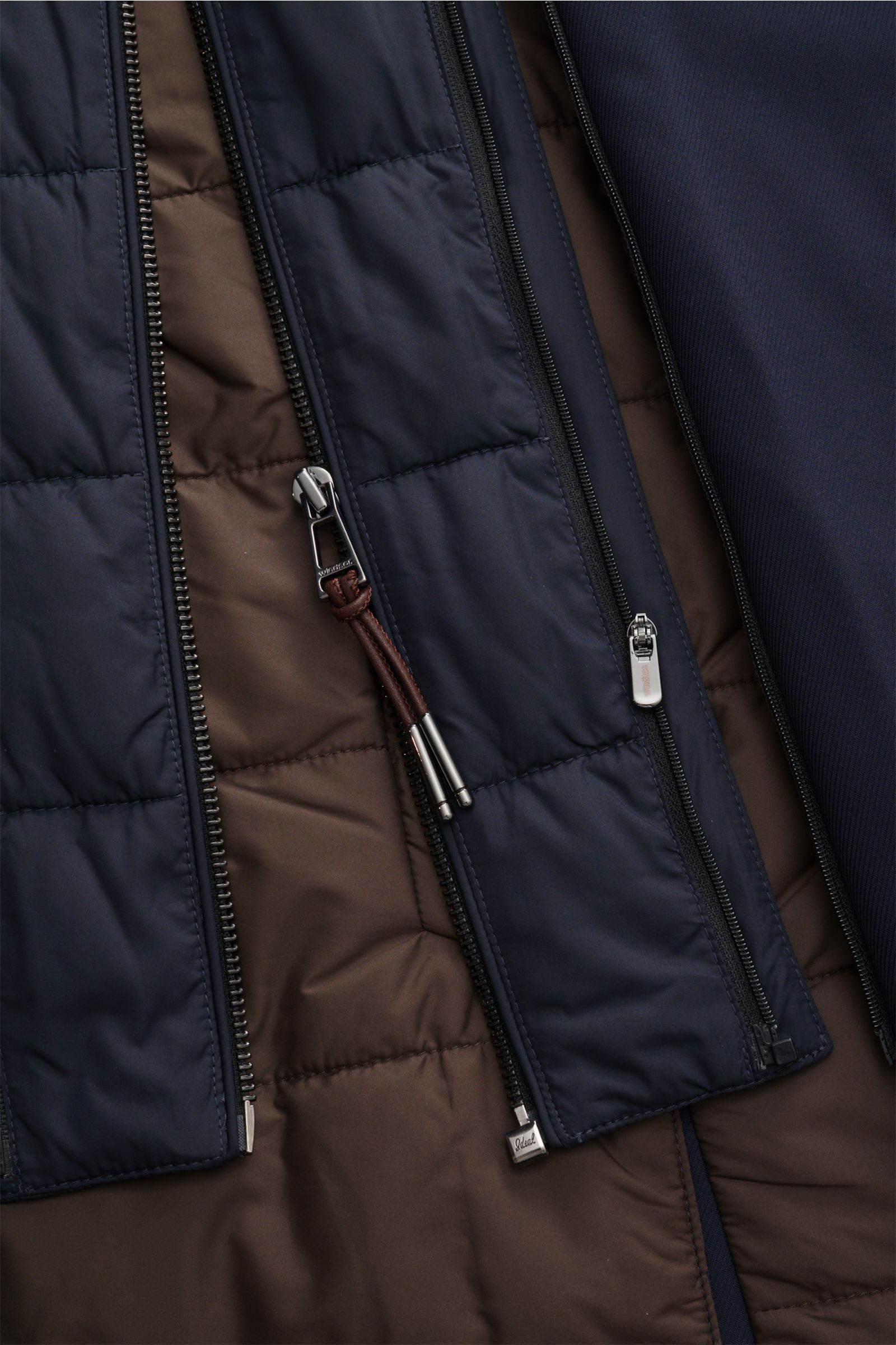 Close-up inside view of Windsor Parka 'Sarno' navy showing lightweight Thermore-wattierung, double-front zipper, and soft lining from a flat-lay perspective, highlighting its versatile design with removable hood and stand collar.

Flexibel bleiben – mi