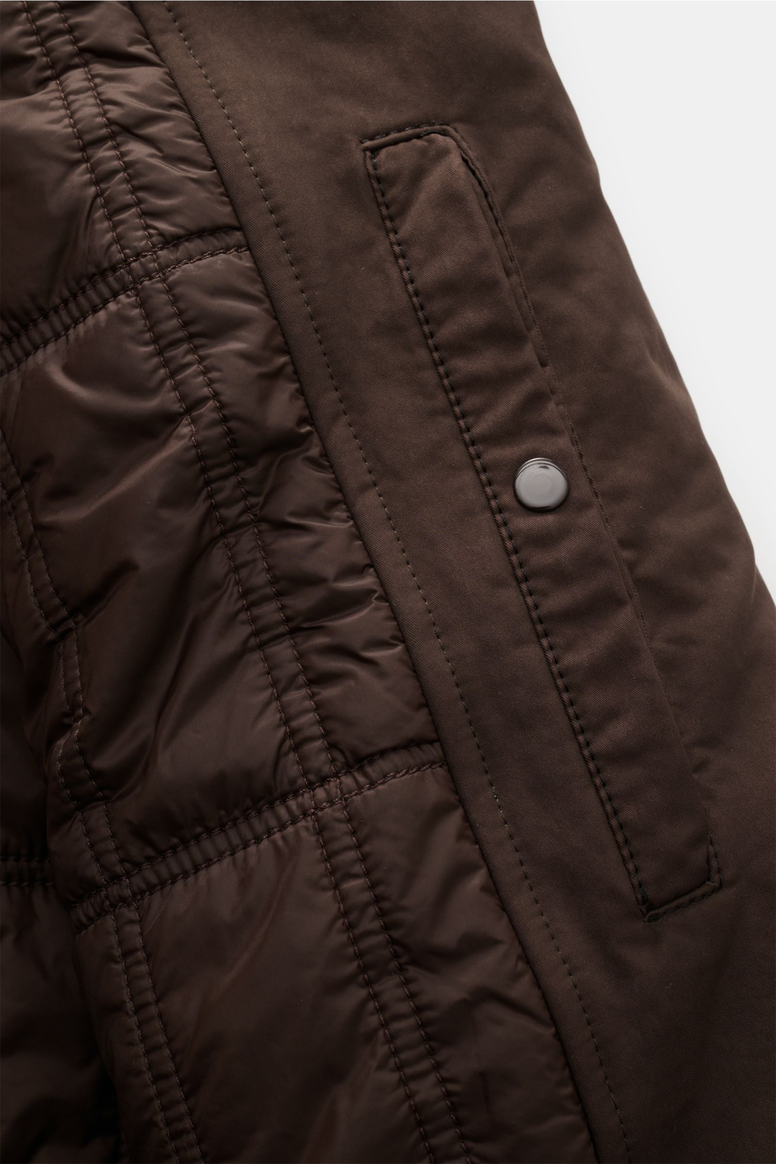 Nahaufnahme der Stone Island Jacke 'David-TC Ghost Piece' dunkelbraun, zeigt gestepptes Innenfutter und schräg überlappende Knopfleiste.