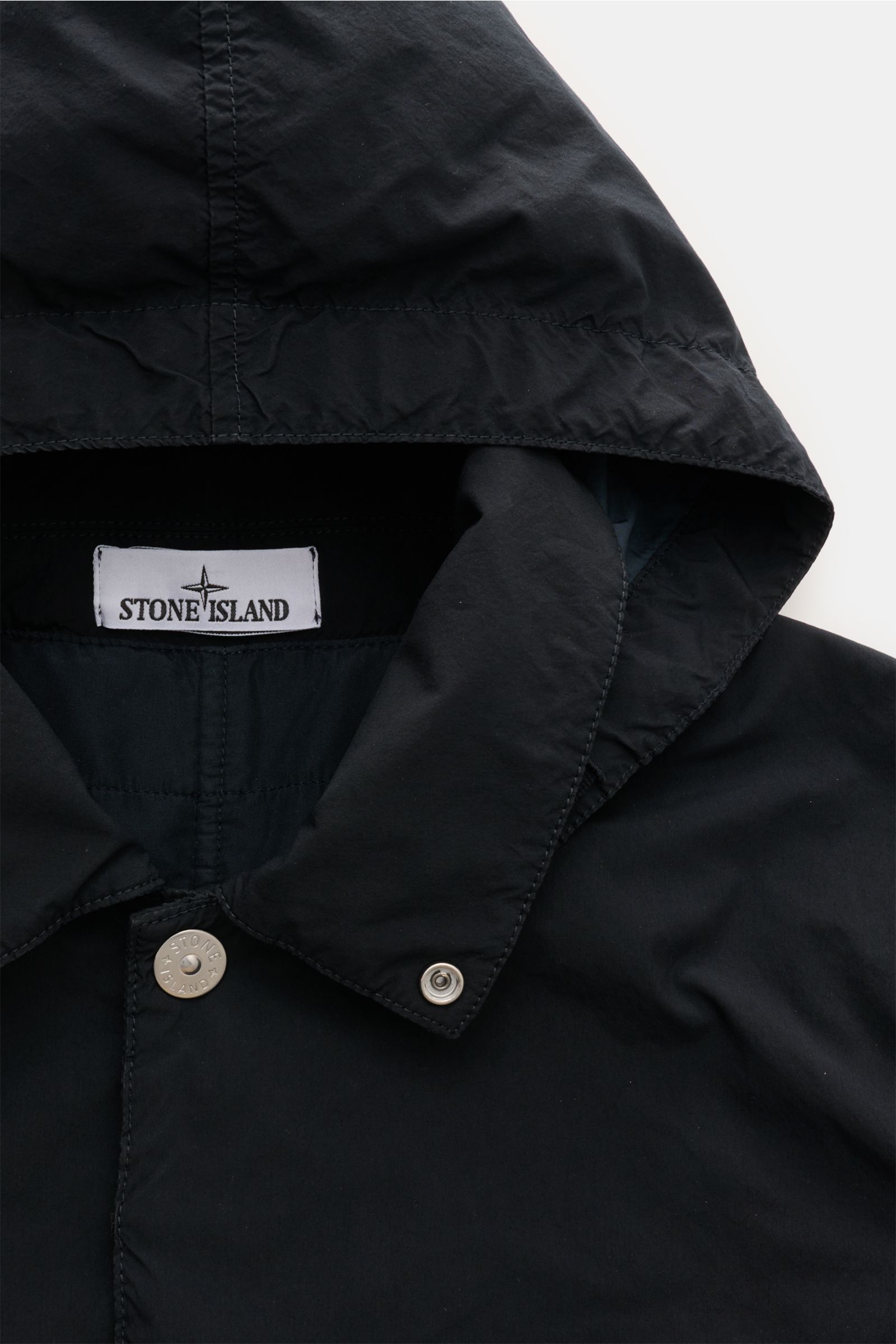 Stone Island Parka 'Light Compact Touch Poly-TC' dark navy in Nahaufnahme von oben, Kapuze, Kragen, Druckknöpfe, typisches Kompass-Badge, elastische Microfaser, wasserabweisend, Slim Fit, leichte Wattierung.