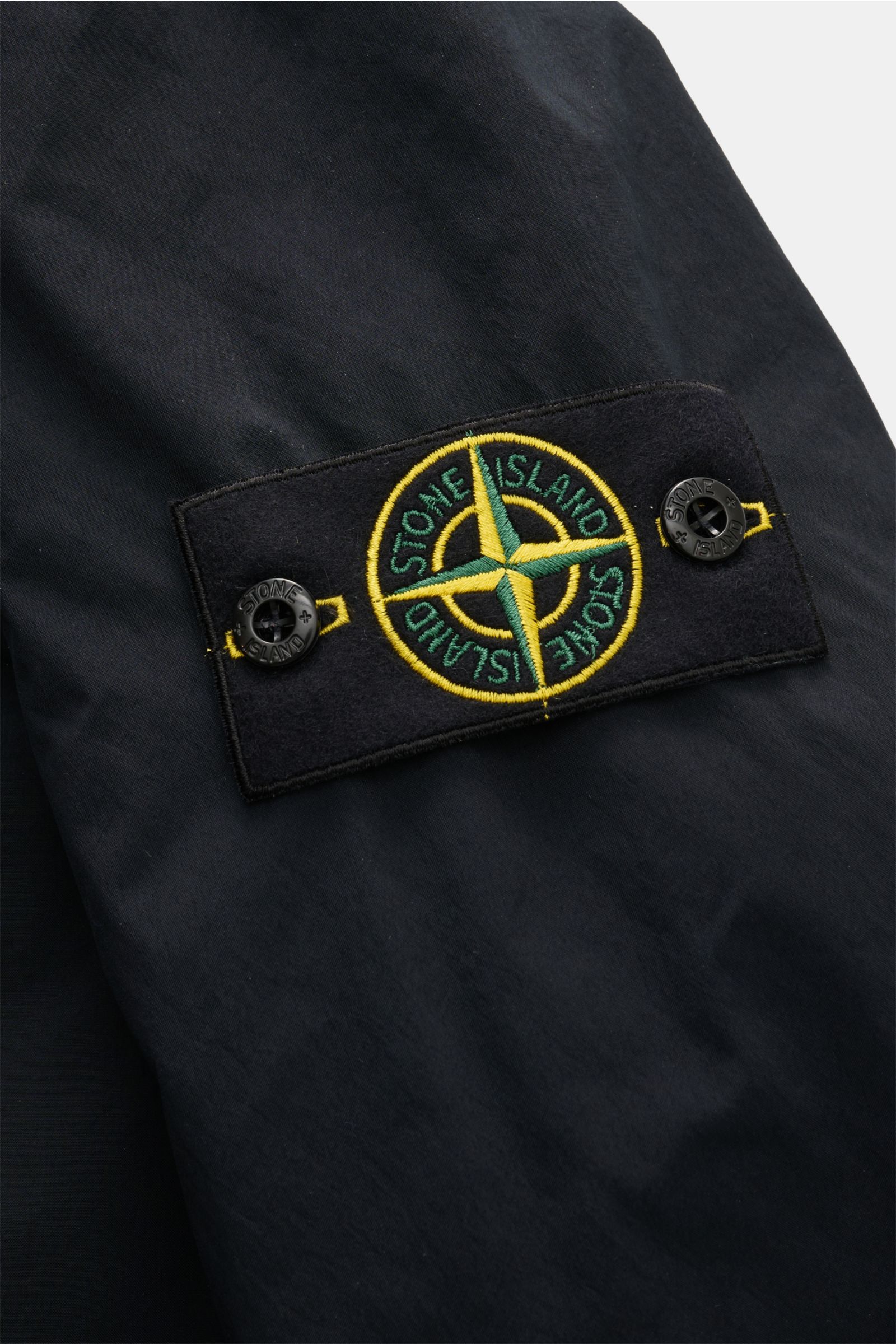 Stone Island Parka 'Light Compact Touch Poly-TC' dark navy, Nahaufnahme des Kompass-Badges auf dunklem, regenabweisendem Material.