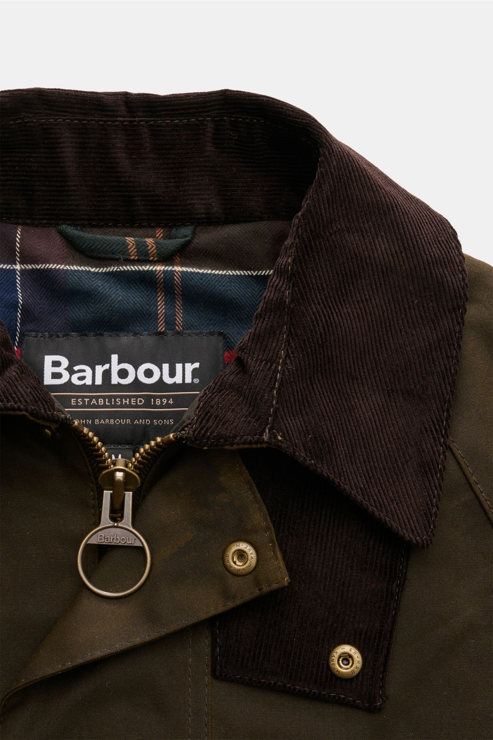 Barbour Wachsparka 'Country' dark olive, Nahaufnahme von gewachster Baumwolle, Cordkragen, Reißverschluss mit Ring und Tartan-Futter.
