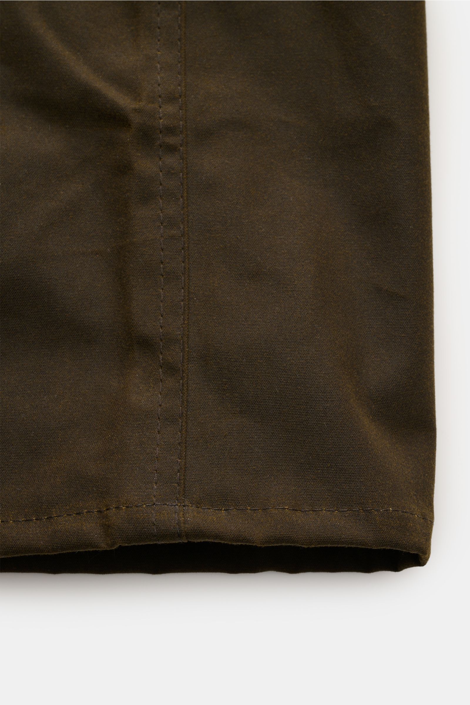 Nahaufnahme des unteren Saums vom Barbour Wachsparka 'Country' dark olive aus gewachster, wasserabweisender Baumwolle in modernem oversized Look.