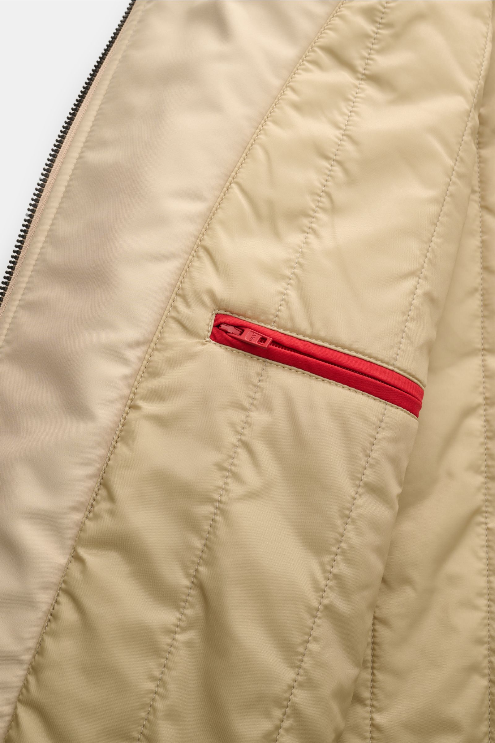 Close-up interior view of the Fay Mantel 'Morning Coat' beige showing the quilted lining, a red zippered inner pocket, and smooth technical microfiber poplin fabric with light padding.

 

Popeline aus technischer Microfaser
glatte
