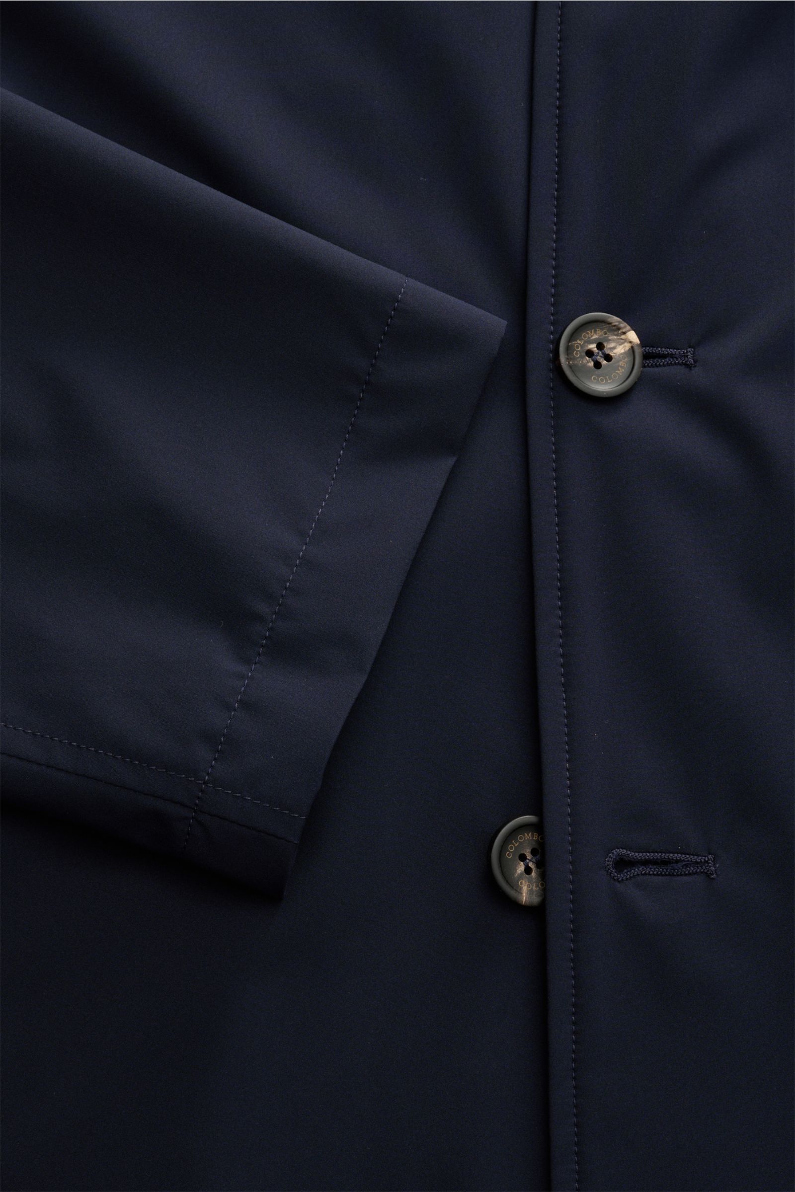 Close-up front view of Colombo Mantel navy showing smooth microfiber fabric, buttons, and subtle stitching details.

Dieser Mantel aus hochwertiger Microfaser vom Traditionshaus COLOMBO verkörpert Luxus in seiner reinsten Form und wird durch den geschm