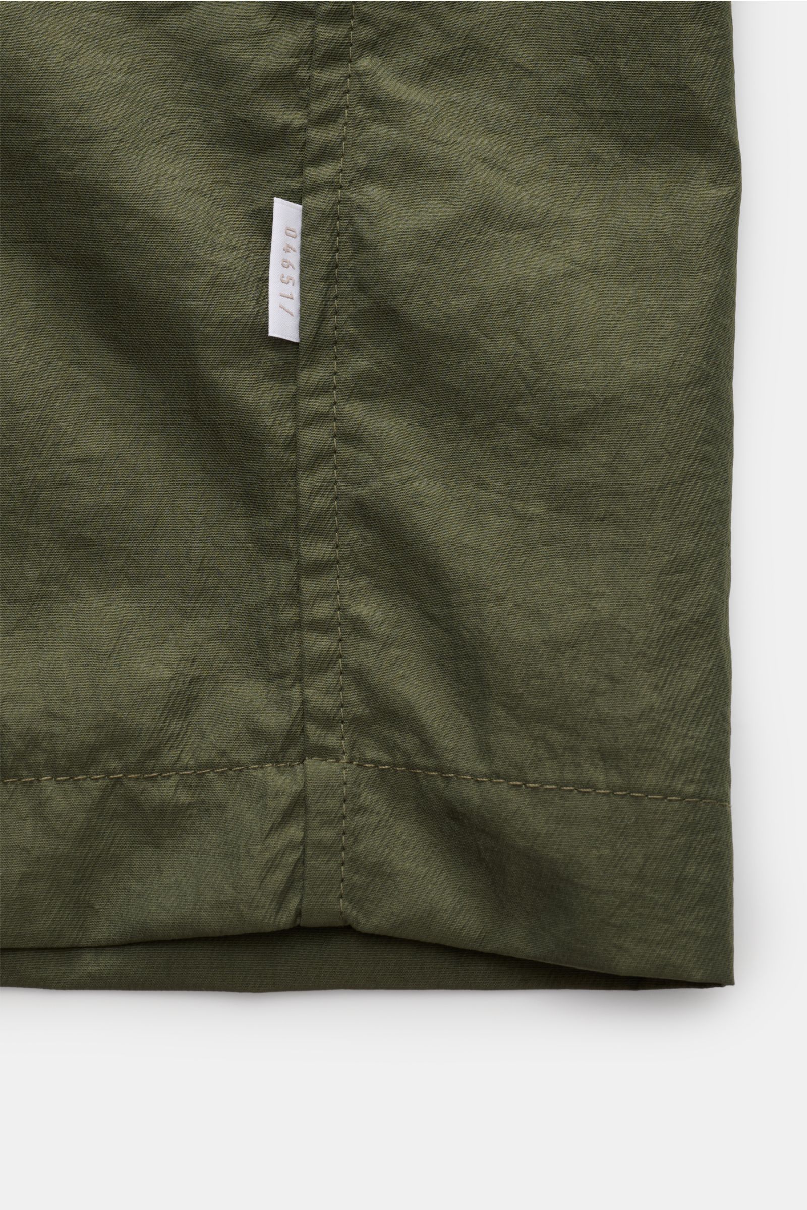 04651/ A trip in a bag Mantel 'Travel Coat' oliv aus wasserabweisender, winddichter Microfaser, Detailansicht des unteren Saums mit Naht und Label.