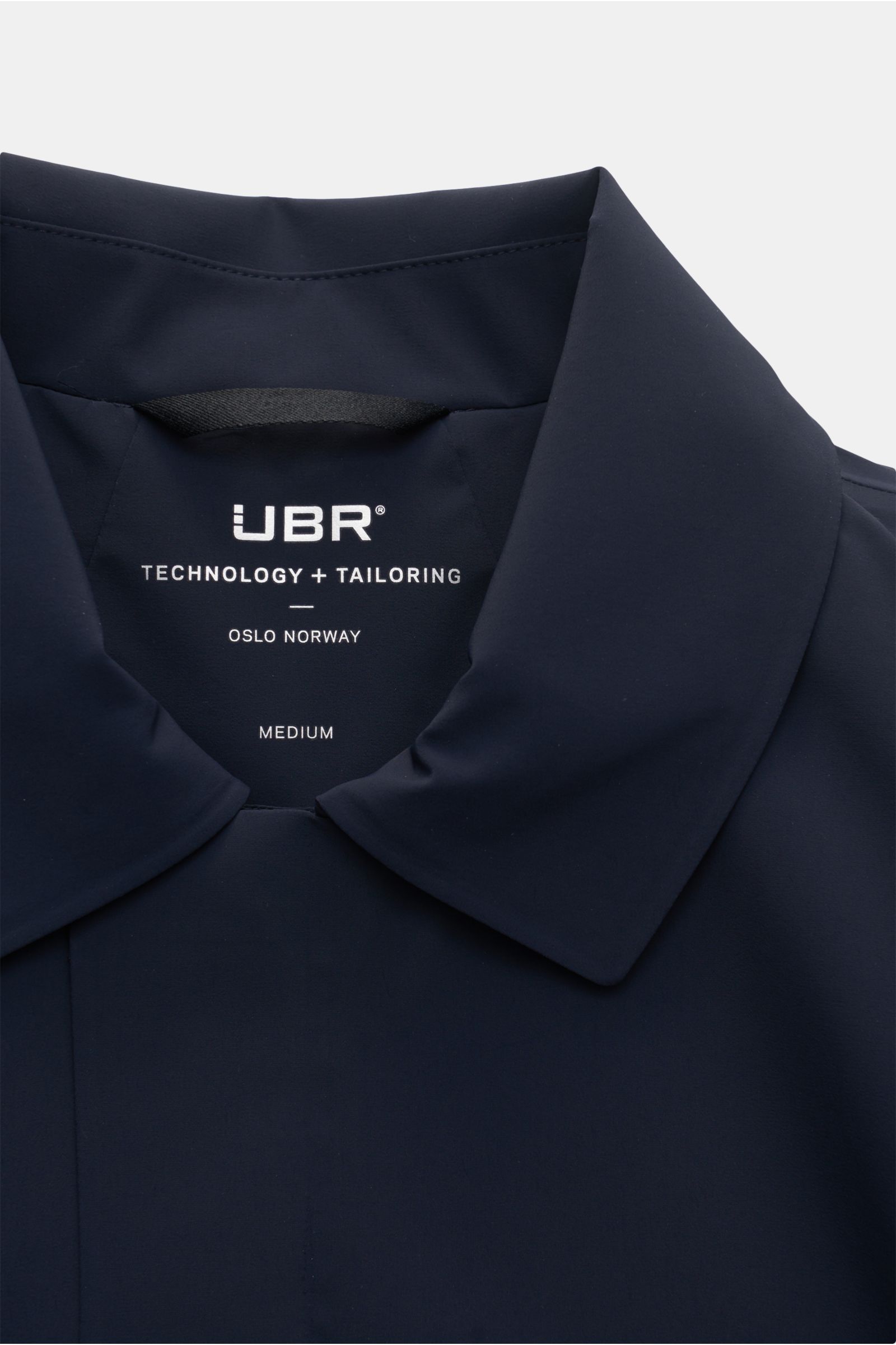 Close-up front view of UBR Kurzmantel 'Regulator Coat' navy showing the collar and label. Leicht und besonders funktional ist das Modell 'Regulator Coat' des norwegischen Labels UBR – skandinavische Simplizität bestimmt das cleane Design des Kurzmantels, 
