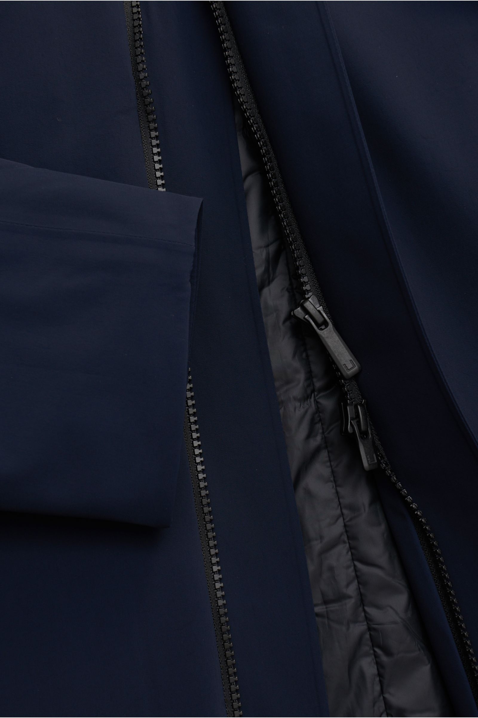 Close-up front view of the navy UBR Kurzmantel 'Regulator Coat' showing bi-elastic microfiber fabric, two-way zipper, and Primaloft lining. Leicht und besonders funktional ist das Modell 'Regulator Coat' des norwegischen Labels UBR – skandinavische Simpli