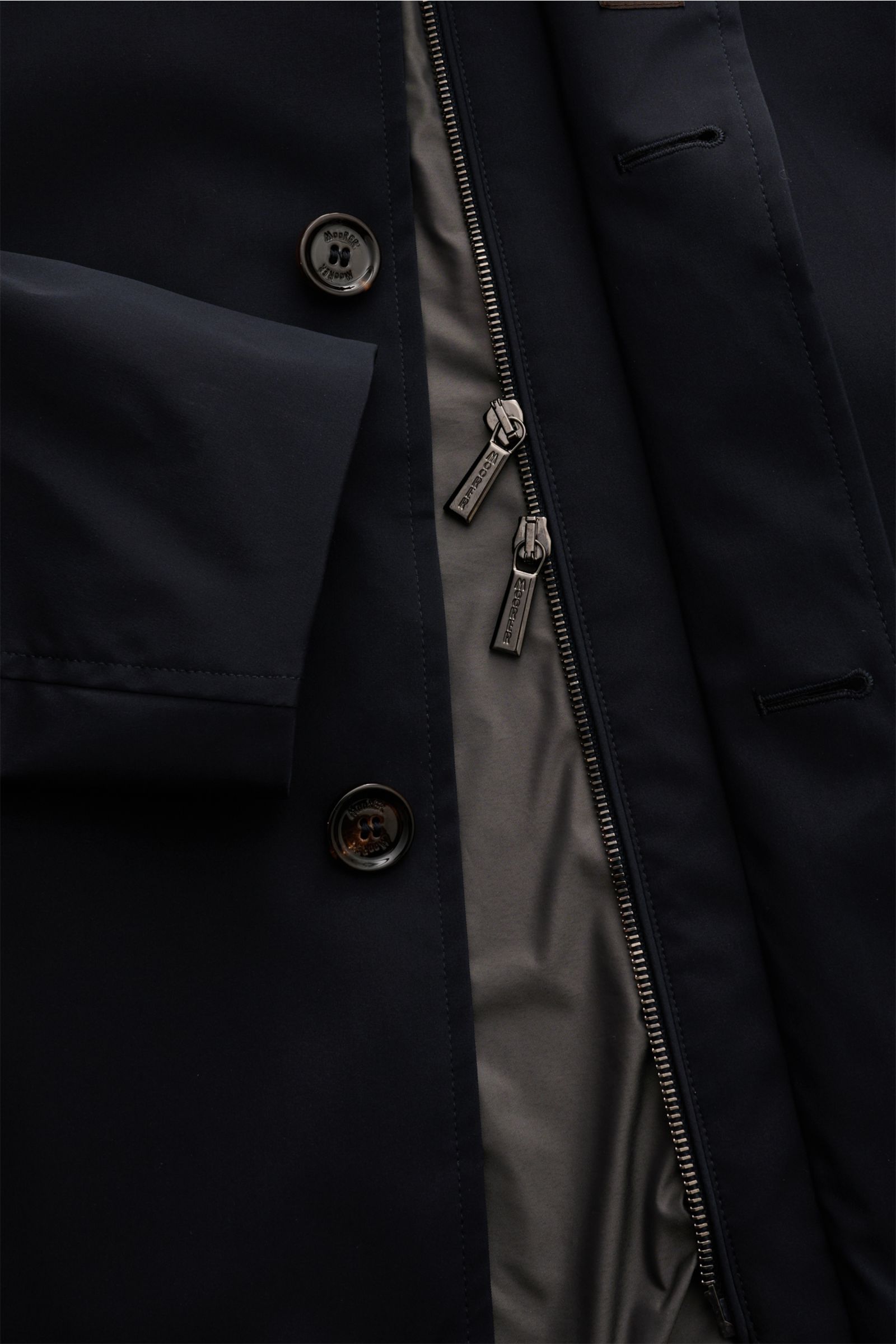 Close-up from above of the navy Moorer Kurzmantel 'Borromini' showing its button and double zipper front, smooth fabric, and inner lining.