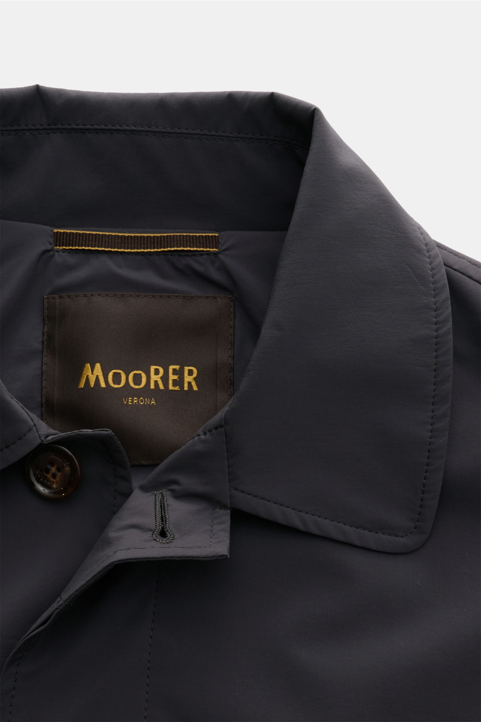 Close-up front view of the collar and label of Moorer Kurzmantel 'Vittor' dunkelgrau, a dark gray short coat made of water-repellent microfiber with a smooth touch, featuring a slim fit, four-button placket, turn-down collar, piped front pockets, buttoned