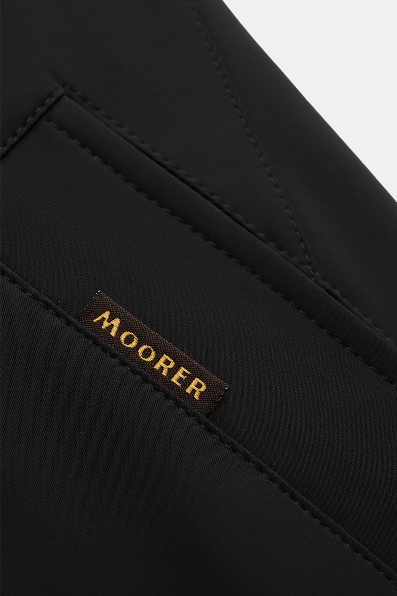 Nahaufnahme des schwarzen Moorer Kurzmantels 'Edgar' mit Fokus auf das Etikett, elastische, wasserabweisende Microfaser, Double-Front, Stehkragen, Slim Fit.