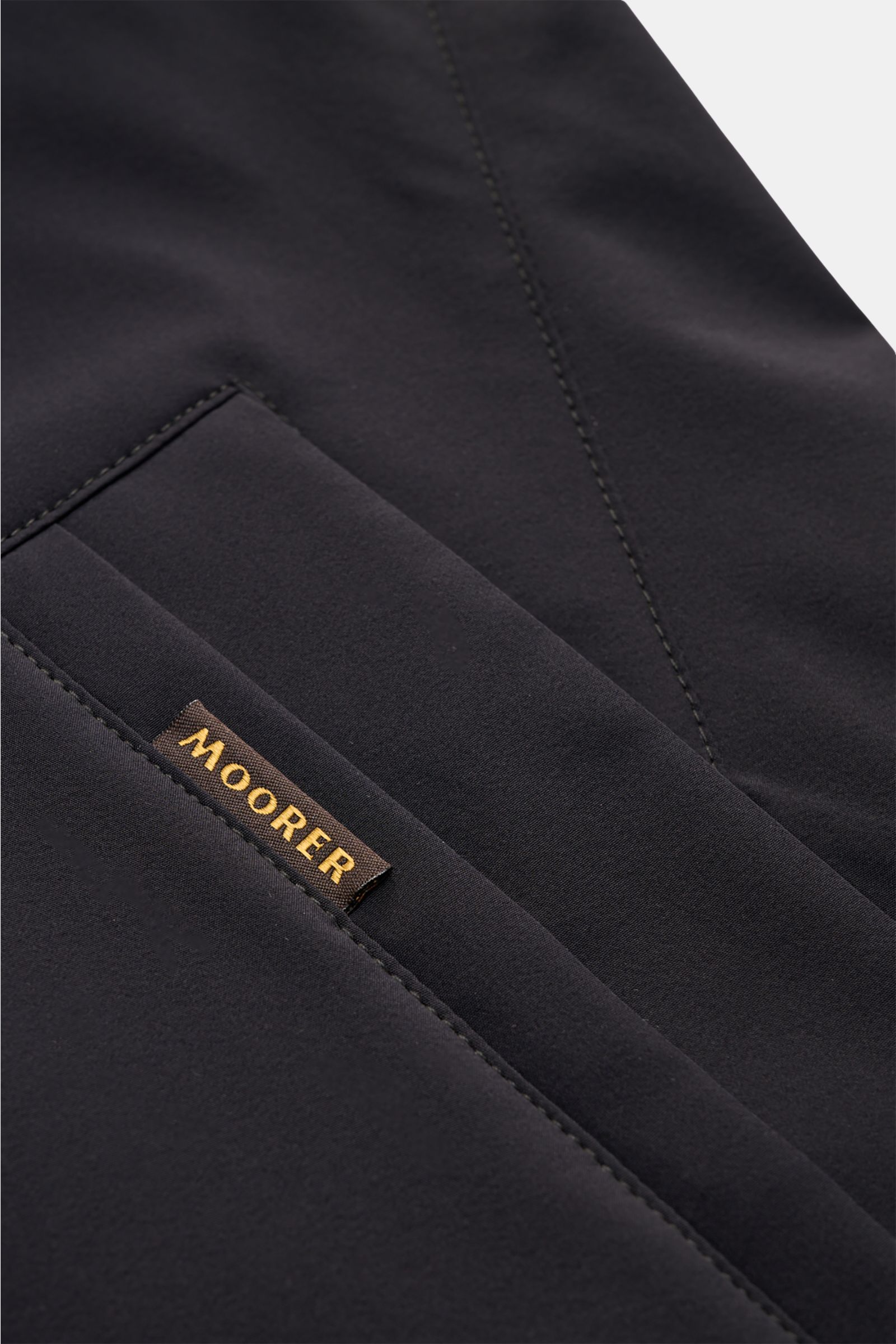 Moorer Kurzmantel 'Hektor' navy Detailfoto schräg von oben auf glatte Microfaser, Leistentasche mit braunem Weblabel, Slim Fit, wasserabweisend.