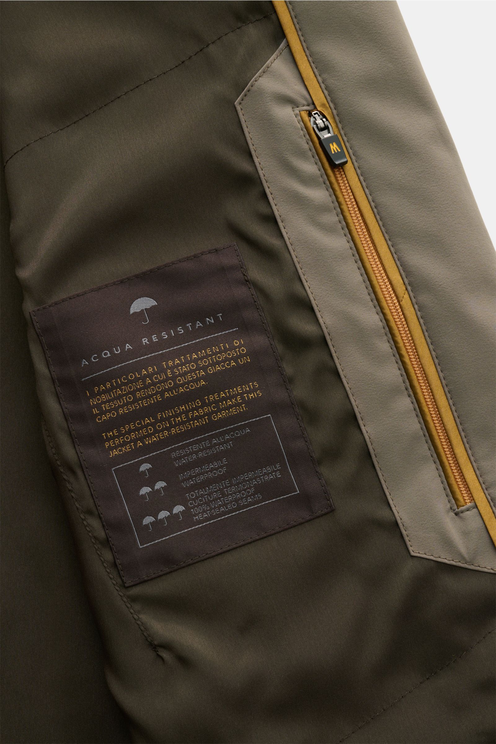 Nahaufnahme des Innenfutters des Moorer Kurzmantels 'Hektor' khaki mit wasserabweisendem Label und Reißverschlusstasche in leichter Microfaser.