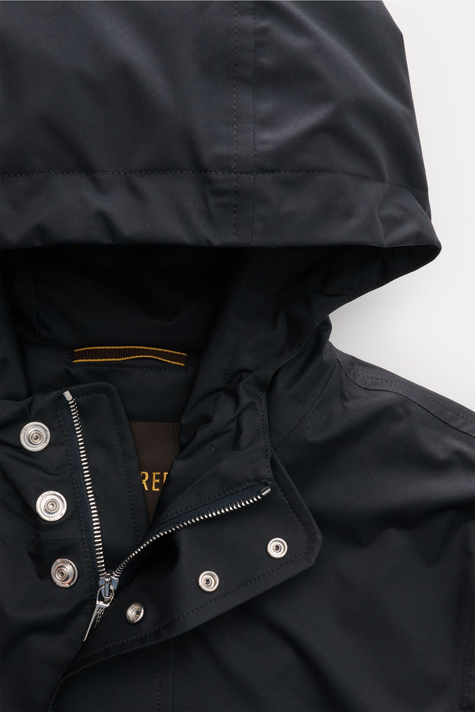 Close-up front top view of Moorer Short coat 'Tiglio' dark navy with waterproof fabric, drawstring hood, two-way zip, and snap-button storm flap, showcasing premium outerwear details for challenging weather.