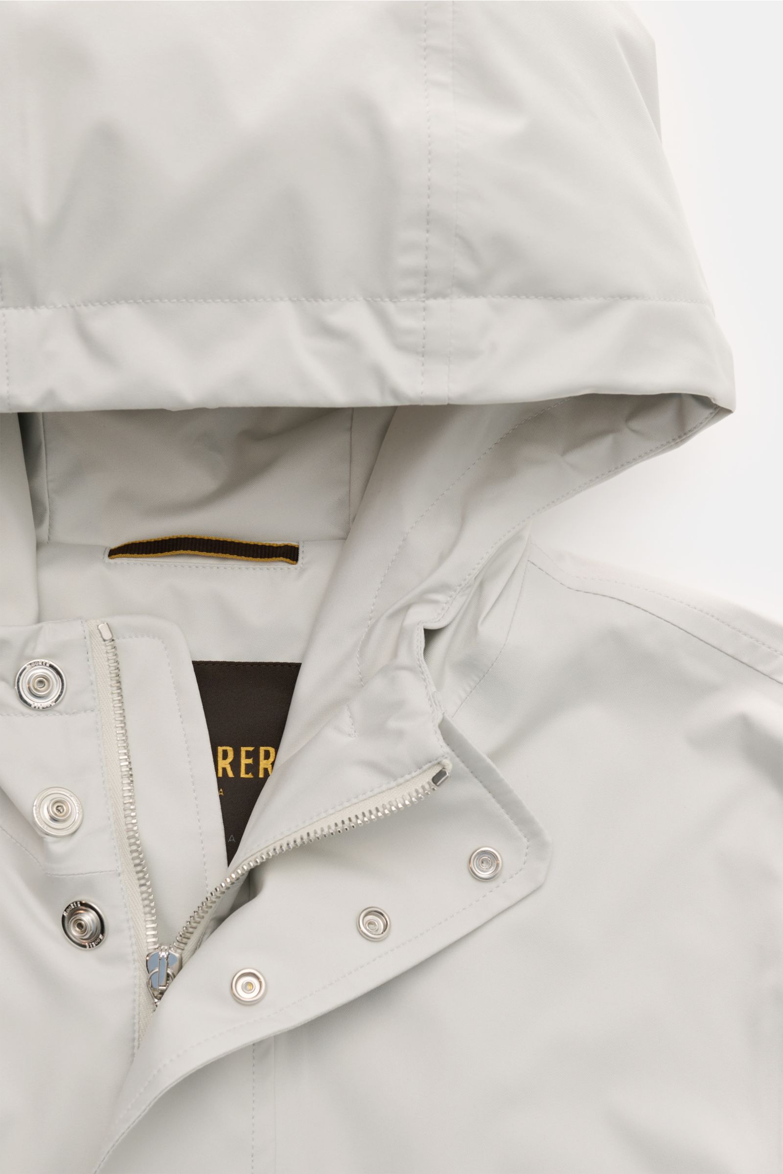 Close-up front view of Moorer Short coat 'Tiglio' light grey, showing waterproof fabric, drawstring hood, two-way zip, snap buttons, and smooth lining, designed for premium outerwear in challenging weather.