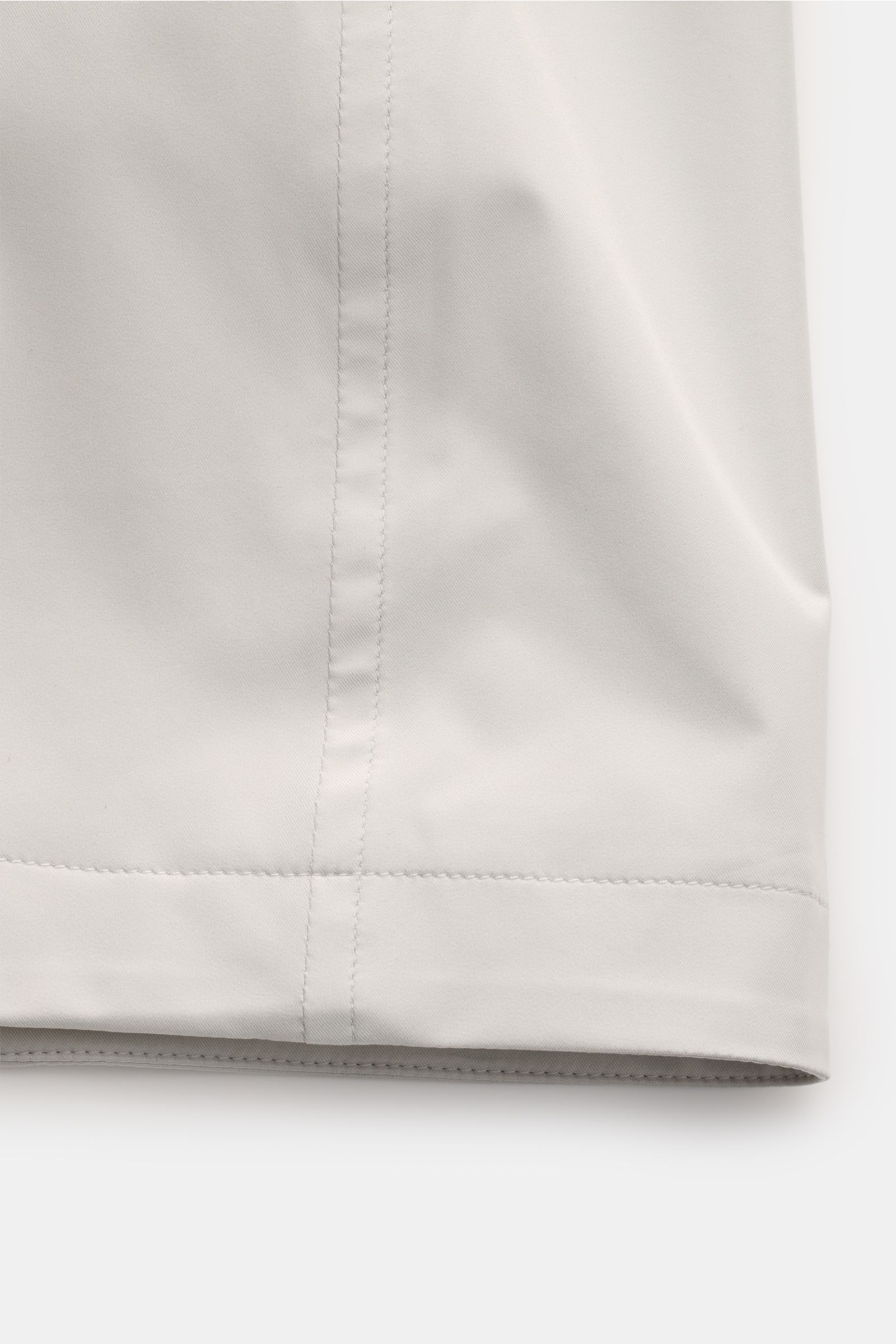 Close-up front view of the lower section of the Moorer Short coat 'Tiglio' light grey, showing smooth, waterproof microfiber fabric with neat stitching. Premium outerwear for challenging conditions: Waterproof fabric, taped seams, and a practical hood mak