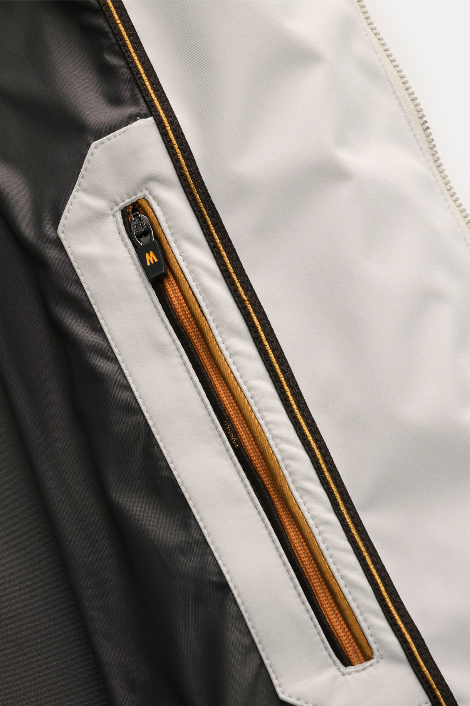 Close-up interior view of Moorer Short coat 'Tiglio' light grey showing waterproof fabric, smooth lining, and detailed zip pocket with orange trim. Premium outerwear for challenging conditions: Waterproof fabric, taped seams, and a practical hood make thi