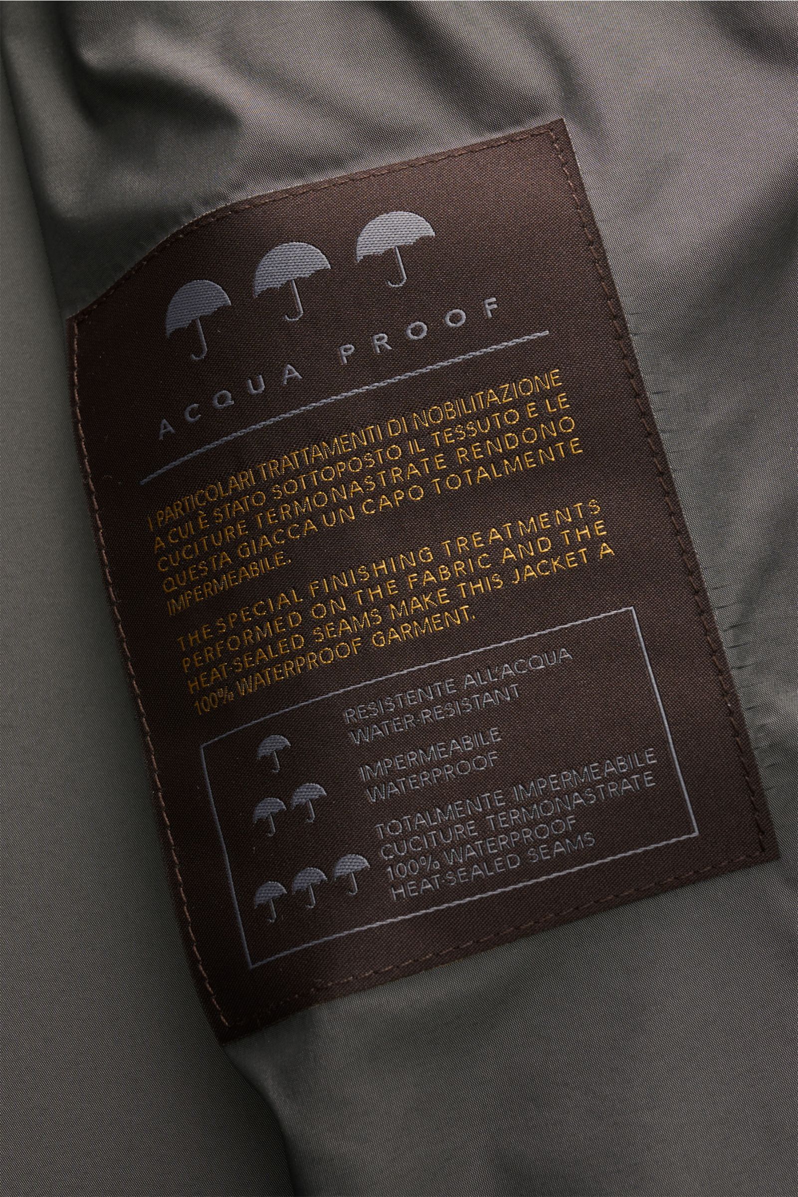 Close-up of the inner label of Moorer Short coat 'Tiglio' light grey, showing waterproof fabric and heat-sealed seams details from a top-down perspective. Premium outerwear for challenging conditions: Waterproof fabric, taped seams, and a practical hood m