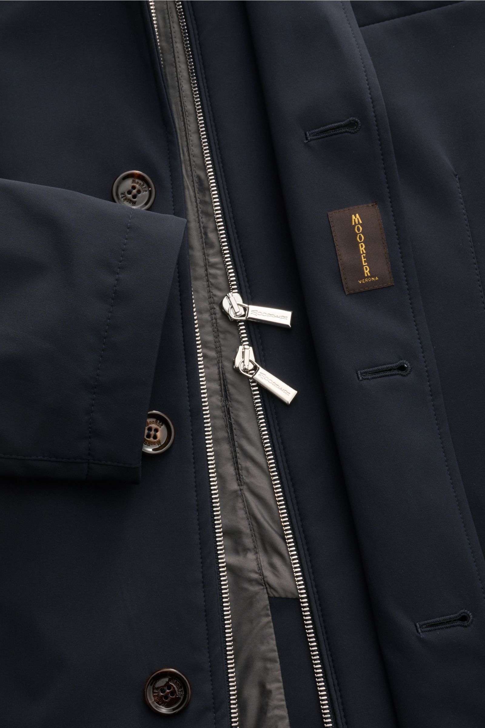 Close-up top view of Moorer Jacket 'Borromeo' navy showing water repellent fabric, double front zipper, buttons, and label.

With its water repellent finish and clean look with double front, the jacket 'Borromeo' by MOORER is the perfect city player an