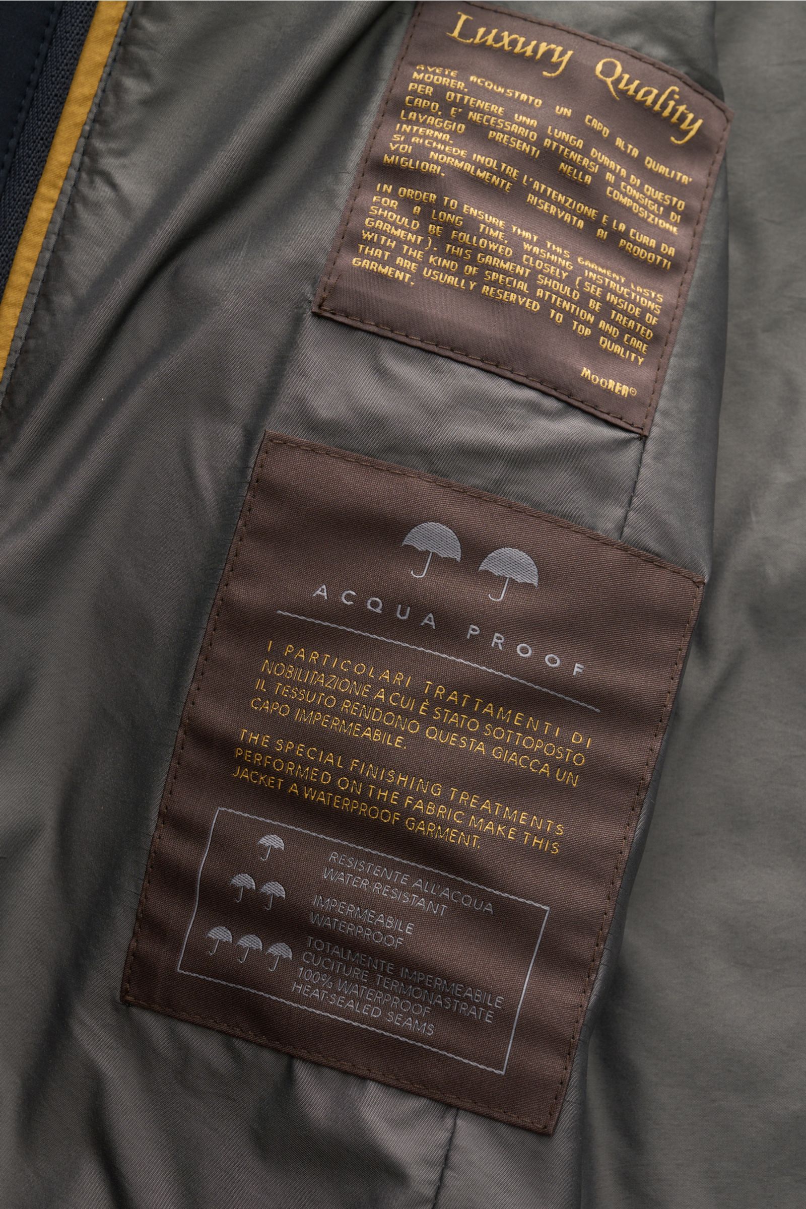 Close-up interior view of the Moorer Jacket 'Borromeo' navy showcasing waterproof labels and smooth lining details.

Description: With its water repellent finish and clean look with double front, the jacket 'Borromeo' by MOORER is the perfect city play