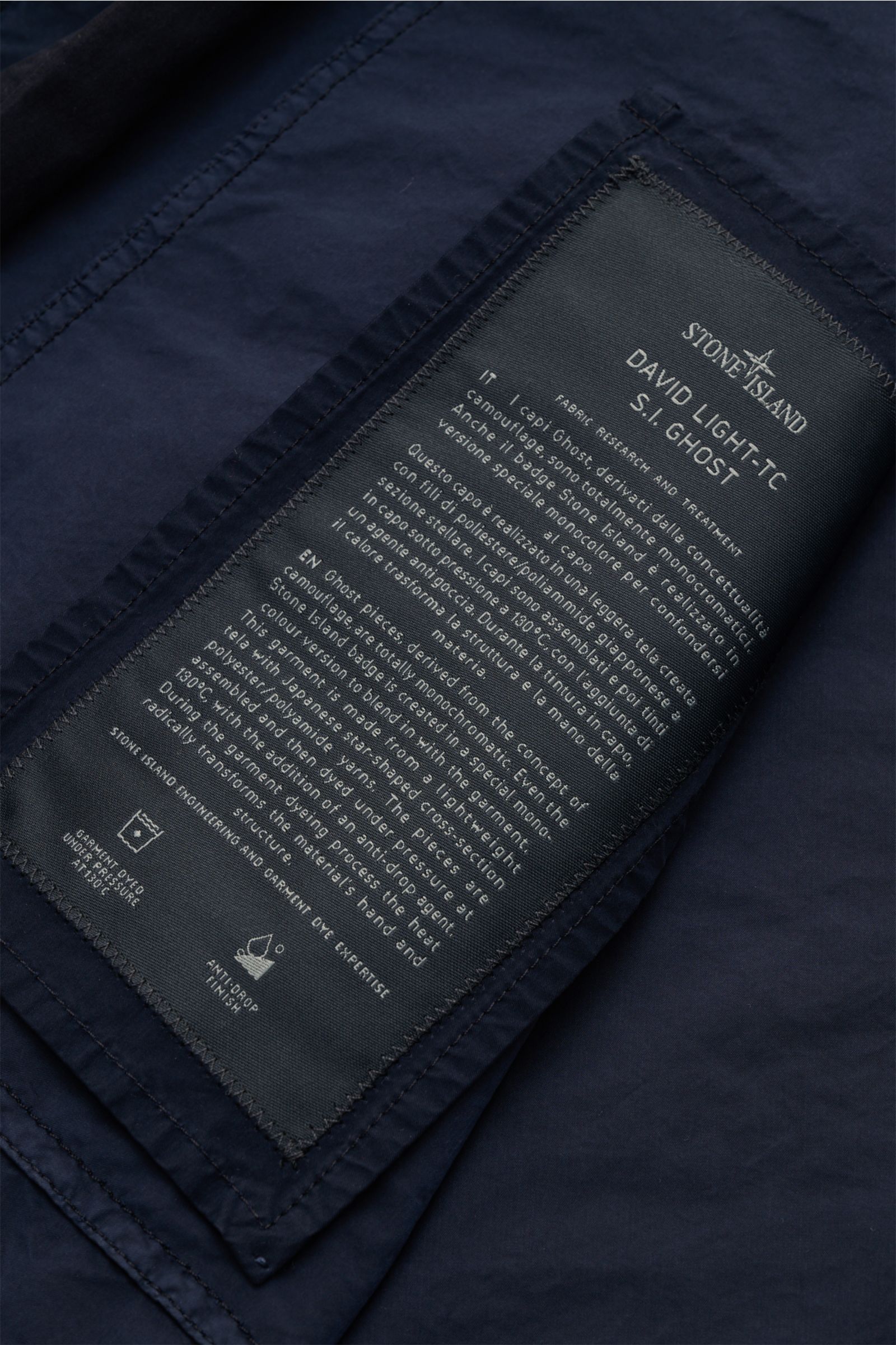 Nahaufnahme des Stone Island Mantel 'Ghost Piece' navy Innenlabels, zeigt Materialbeschreibung in 'David Light-TC'-Qualität, blaue Microfaser.