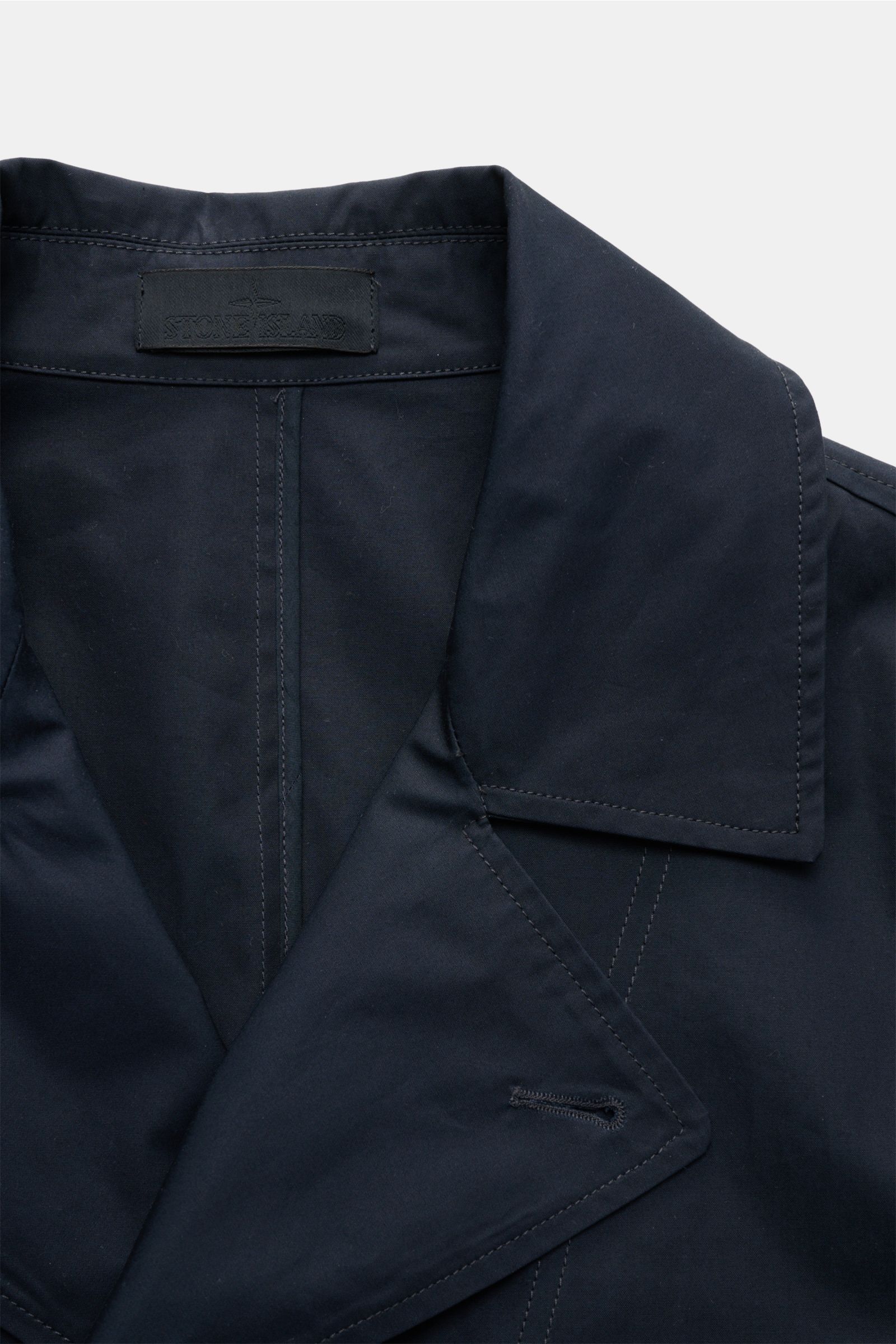 Close-up front view of Stone Island Kurzmantel 'Ghost Piece' navy, showcasing the elegant lapel, smooth water-repellent microfiber popeline with tonal stitching. Eleganz trifft Funktion: Der Kurzmantel von STONE ISLAND aus der 'Ghost-Collection' überzeugt