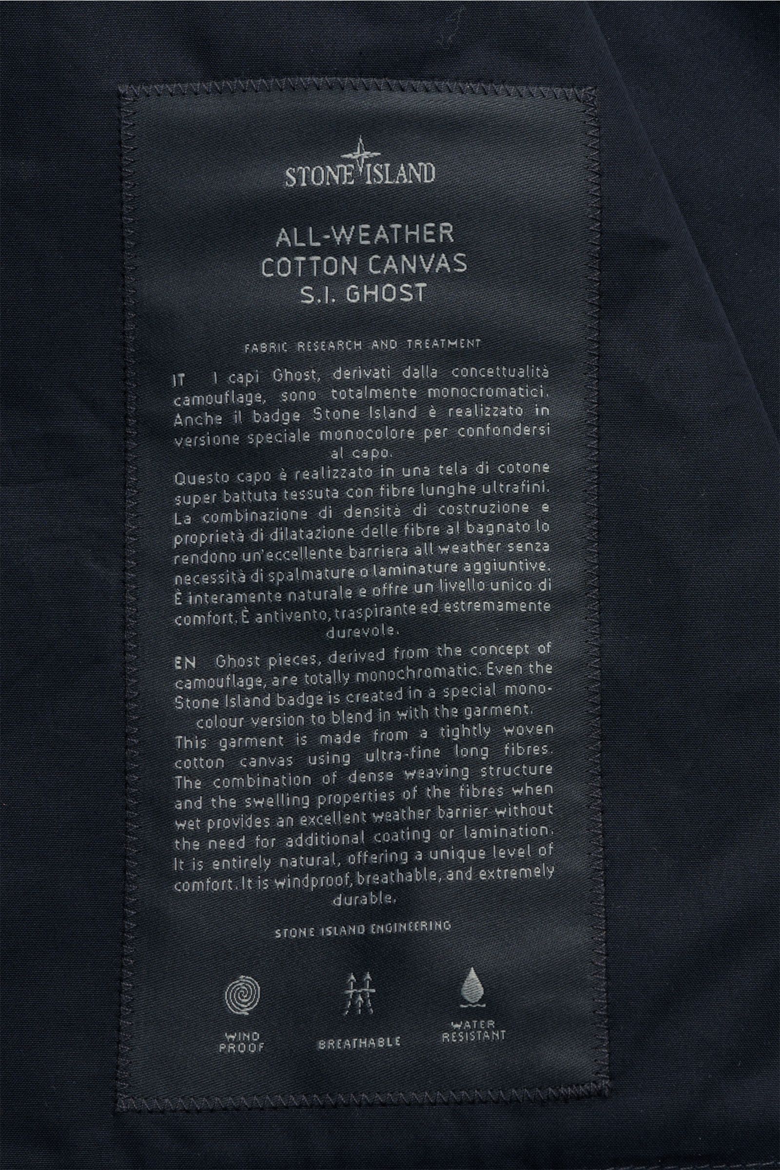 Stone Island Kurzmantel 'Ghost Piece' navy label close-up from above, showing fabric details and care text, Eleganz trifft Funktion: Der Kurzmantel von STONE ISLAND aus der 'Ghost-Collection' überzeugt mit wasserabweisendem Popeline und tonalem Kompass-Ba