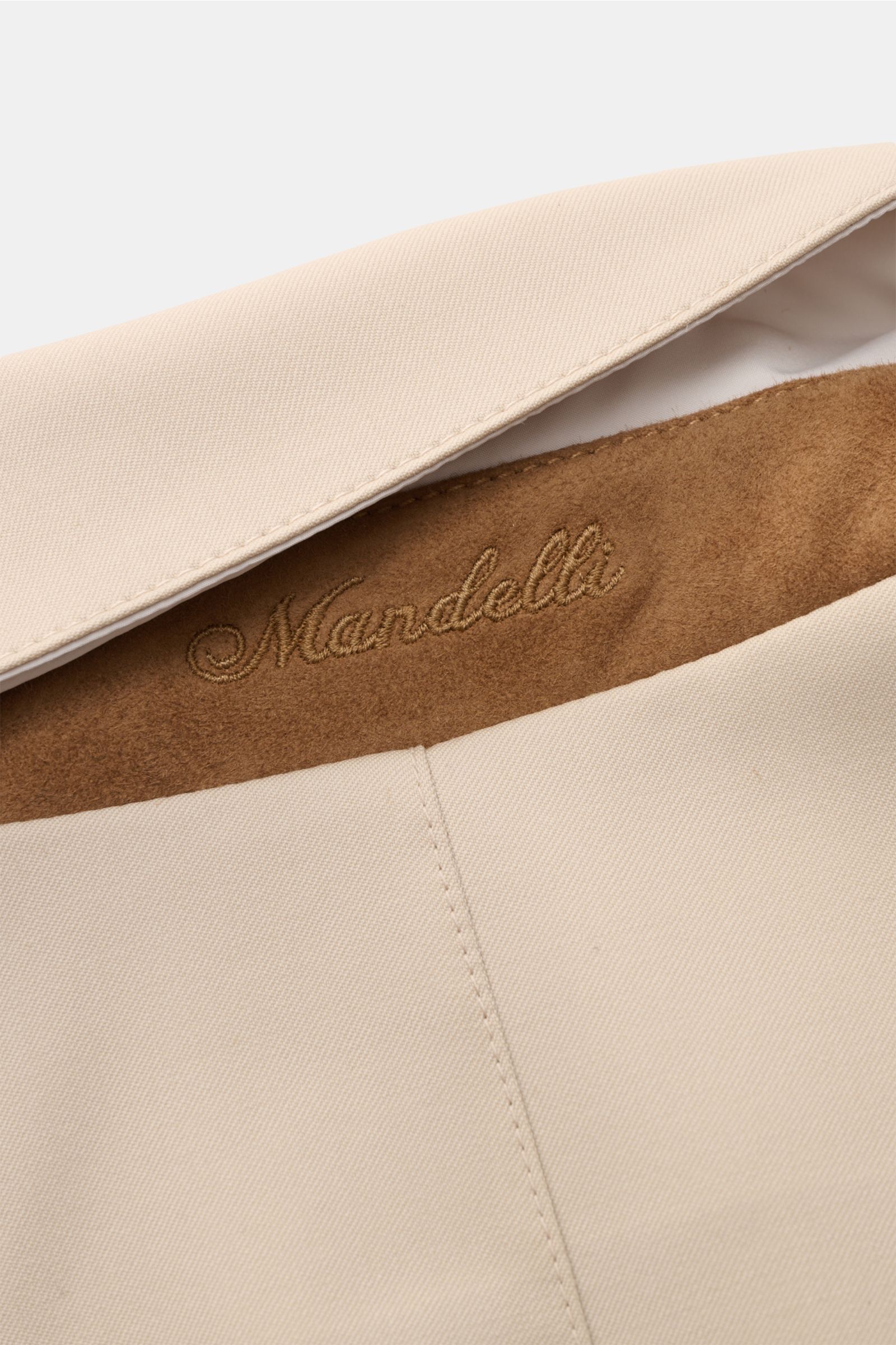 Mandelli Wende-Kurzmantel sand, Detailaufnahme von oben, weicher Wollstoff mit gesticktem Markenlogo innen am Umlegekragen.