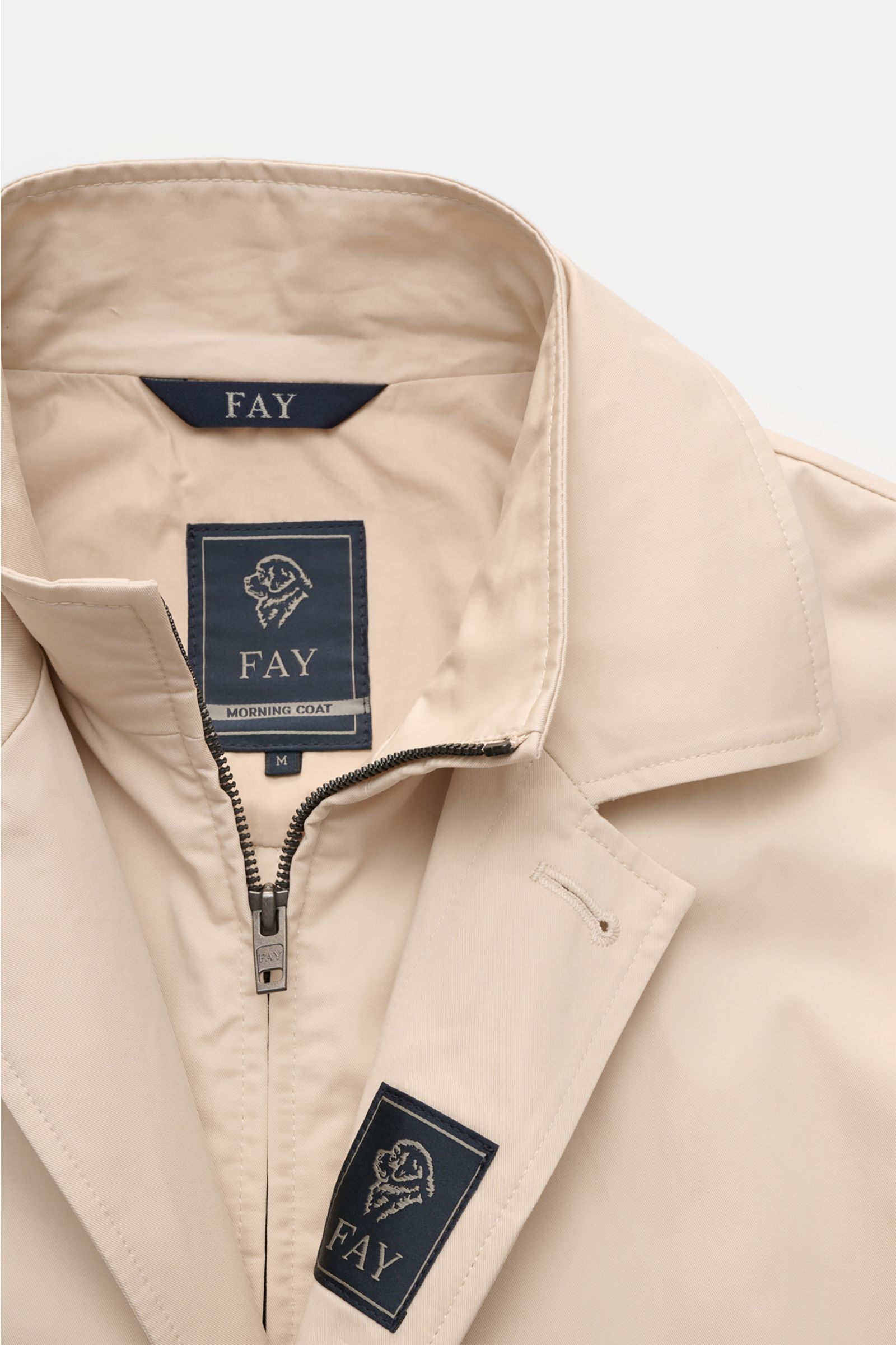 Close-up front view of the Fay Coat 'Morning' sand in pure cotton twill, showing collar, inner zip double front, concealed button placket, and signature woven label. A classic all-rounder for transitional periods with a smooth feel, slim fit, adjustable c