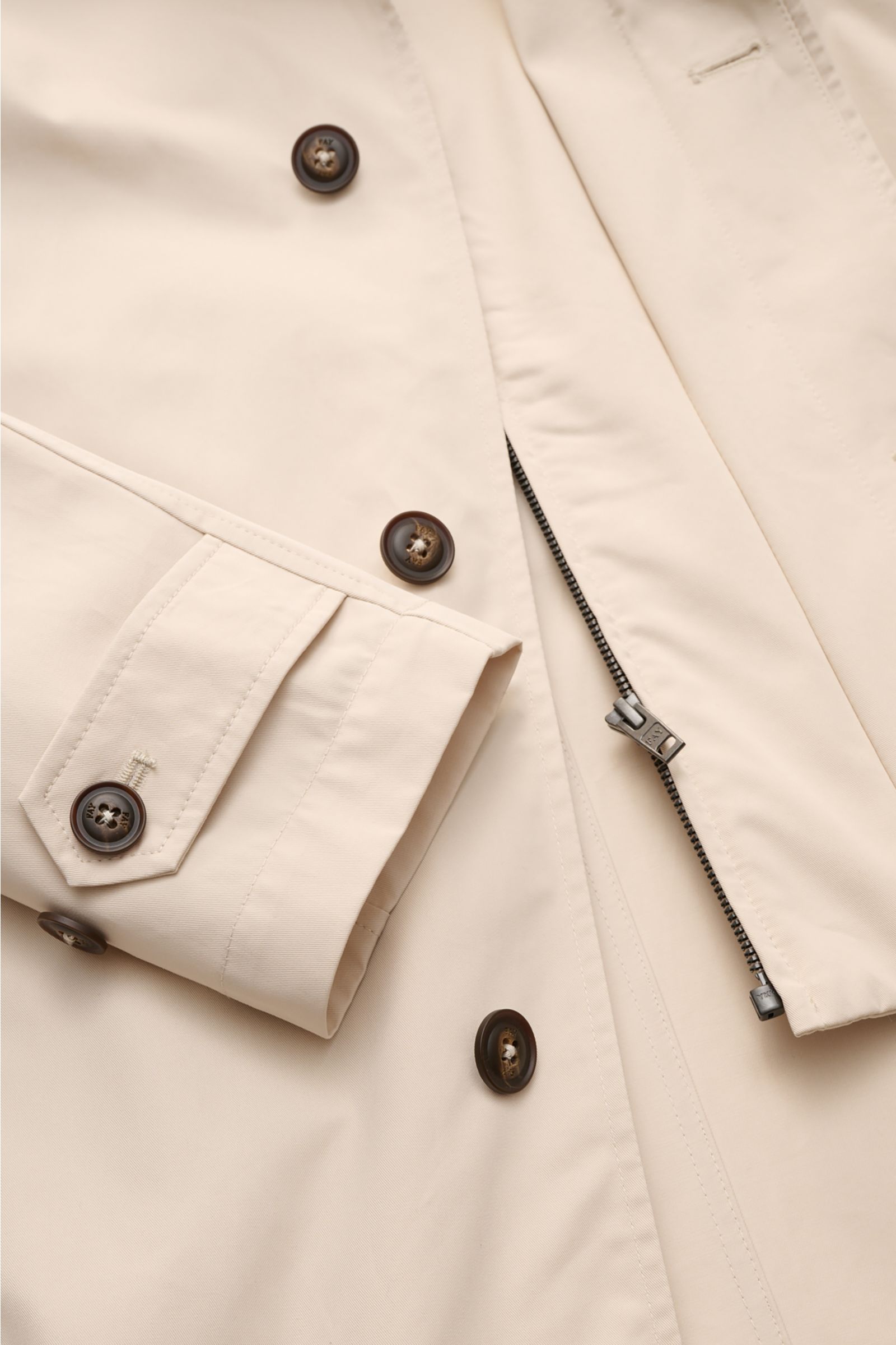 Close-up front detail of Fay Coat 'Morning' sand in pure cotton twill, showing slim fit, zip double front, concealed button placket, adjustable cuff with button tab, photographed from a flat lay top-down perspective.