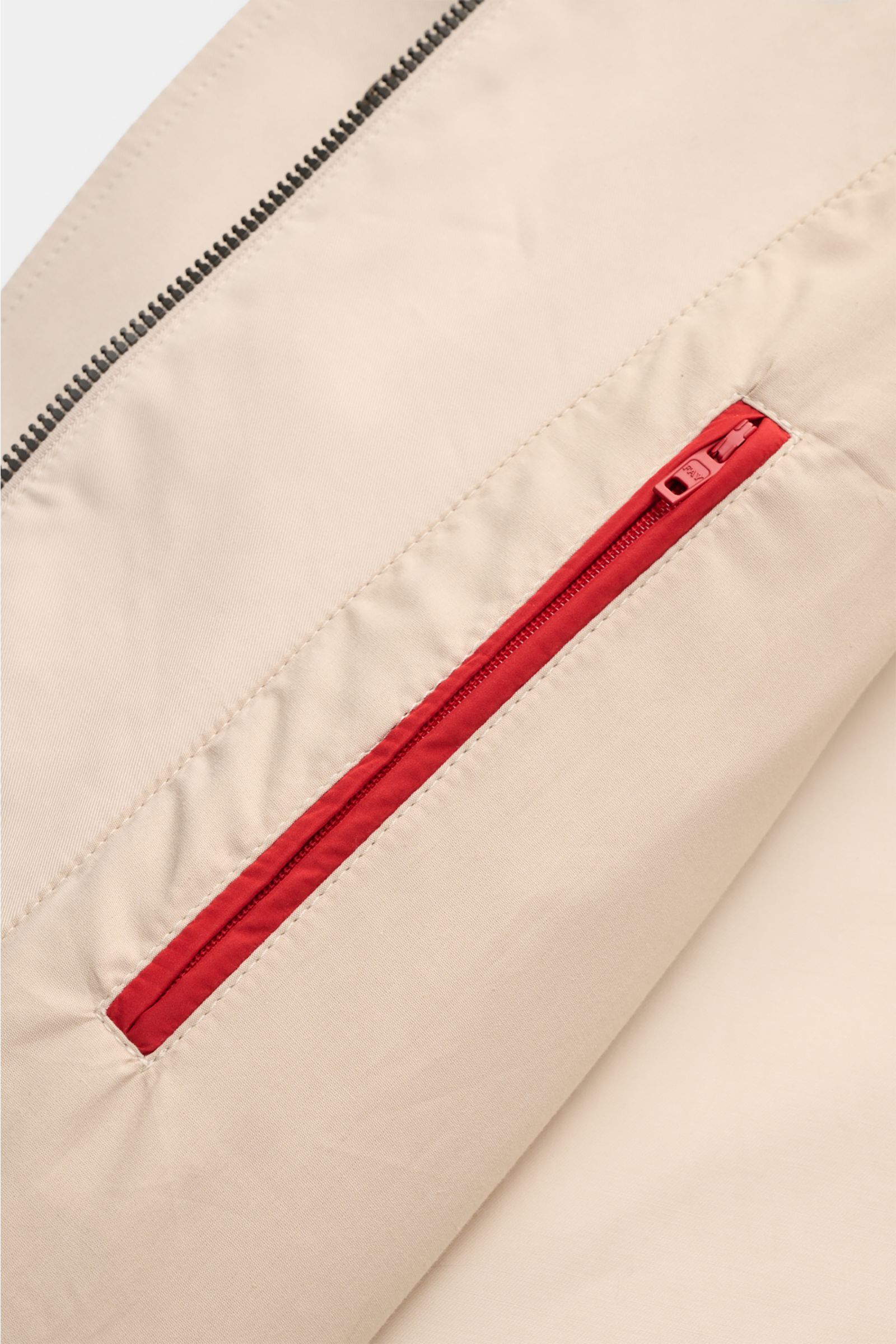 Close-up view of the Fay Coat 'Morning' sand showing the cotton twill fabric, red zip double front, and concealed button placket details.