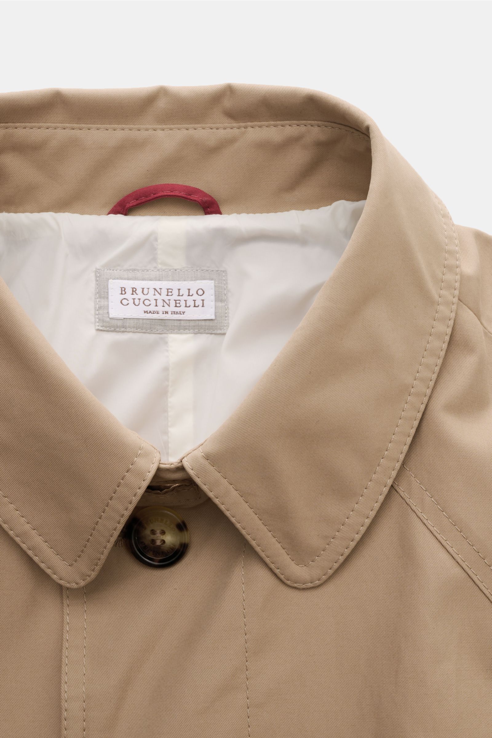 Close-up front view of the beige Brunello Cucinelli Trenchcoat collar and top button, made from water-repellent, breathable cotton and microfiber gabardine. Wasserabweisend und atmungsaktiv: Ein innovativer Mix aus Baumwolle und Microfaser ist die Grun