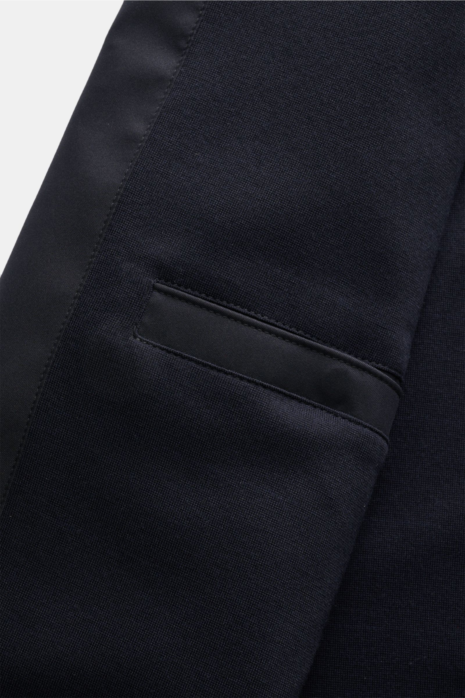 Nahaufnahme des Zegna Mantels 'Motorino' dark navy von schräg oben, Fokus auf Mikrofasermaterial, schräger Hüfttasche und Veloursleder-Kragenbesatz.