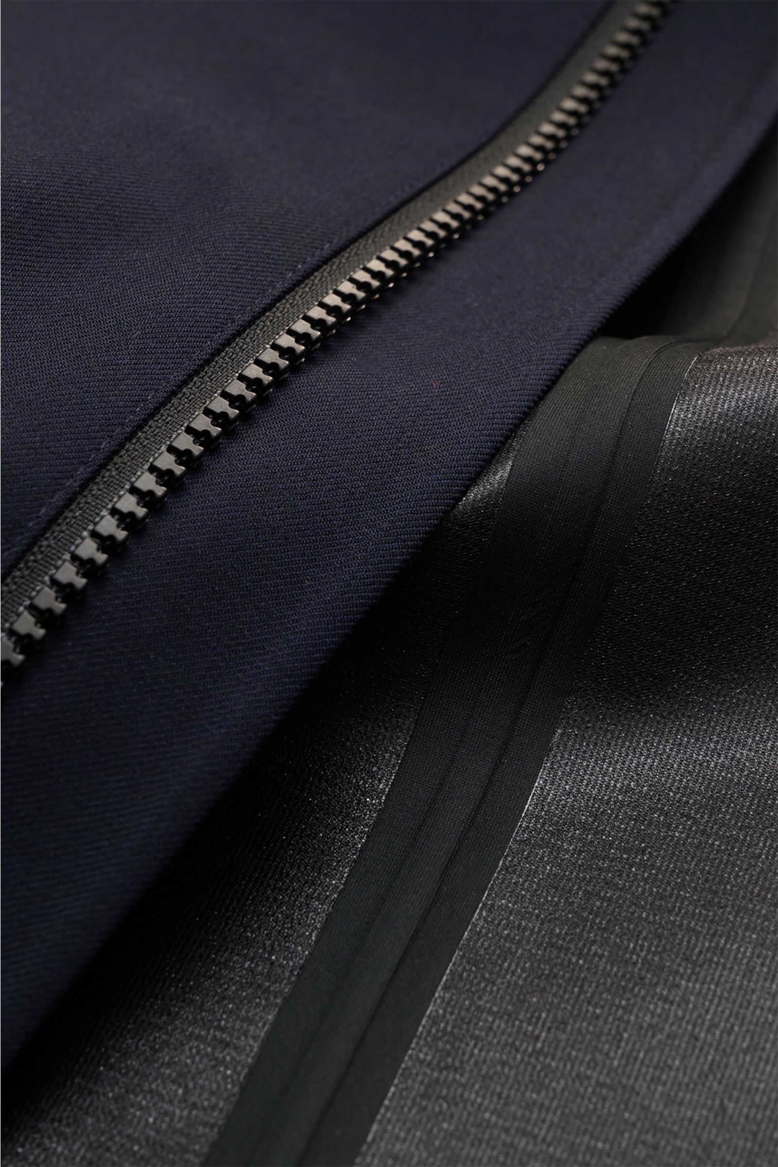 Nahaufnahme des Reißverschlusses und der getapten Nähte des UBR Regenmantels 'Sky Fall Savile' navy aus Merinowolle und Microfaser.