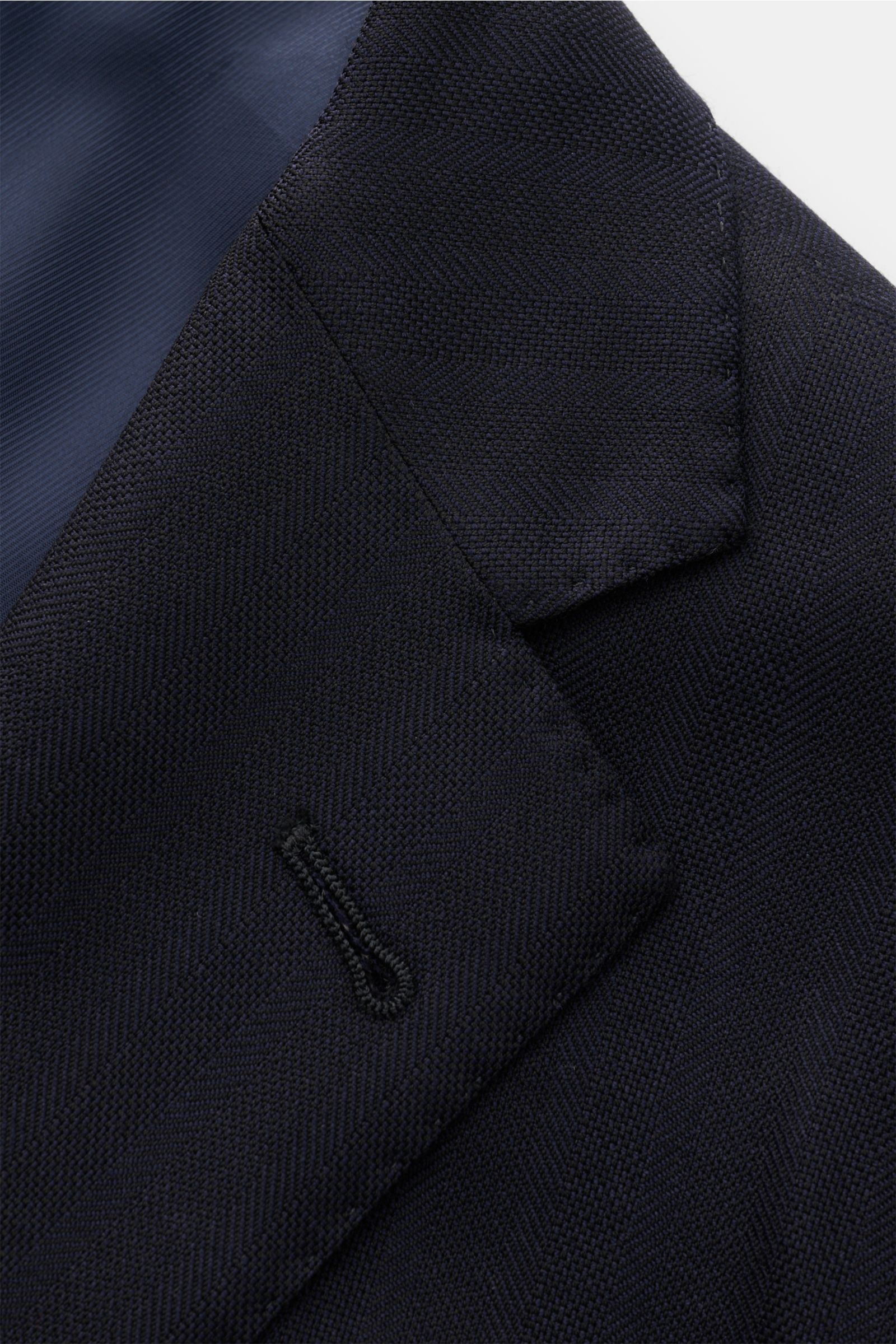 Corneliani Anzug dark navy aus reiner Schurwolle, tonaler Fischgrat, Detailaufnahme des taillierten Zwei-Knopf-Sakkos von schräg oben.