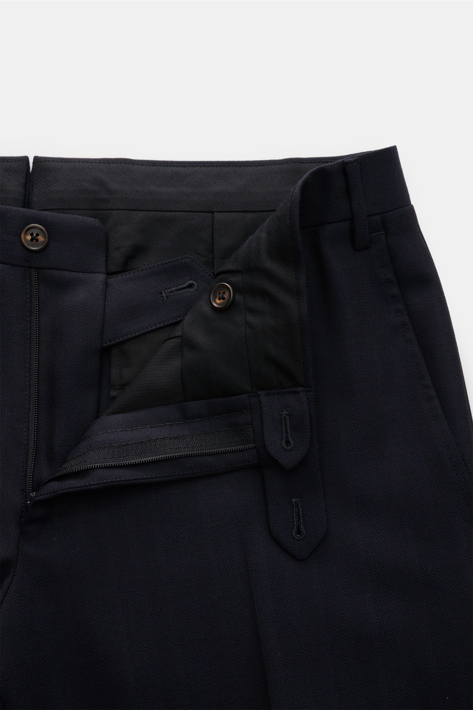 Corneliani Anzug dark navy, Detailaufnahme der Hose mit offenem Bund, Reißverschluss, Knöpfen, tonaler Fischgratstruktur aus Schurwolle.