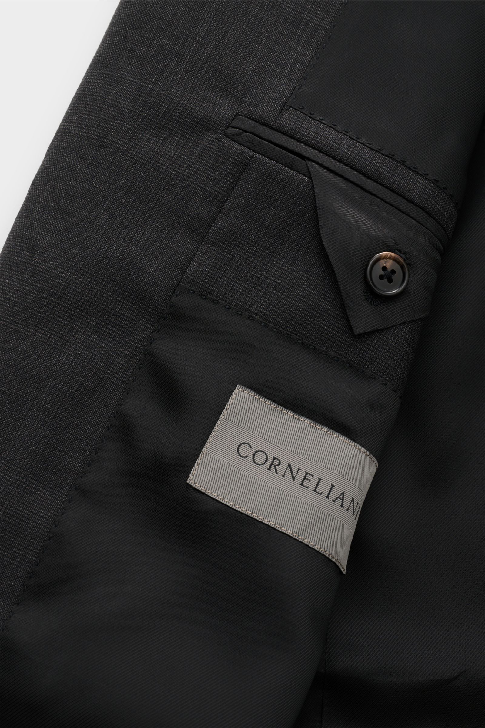 Close-up view of the inside pocket and label of the Corneliani Anzug anthrazit meliert, showing the black lining, buttoned flap pocket, and fine woven pure wool fabric. 
